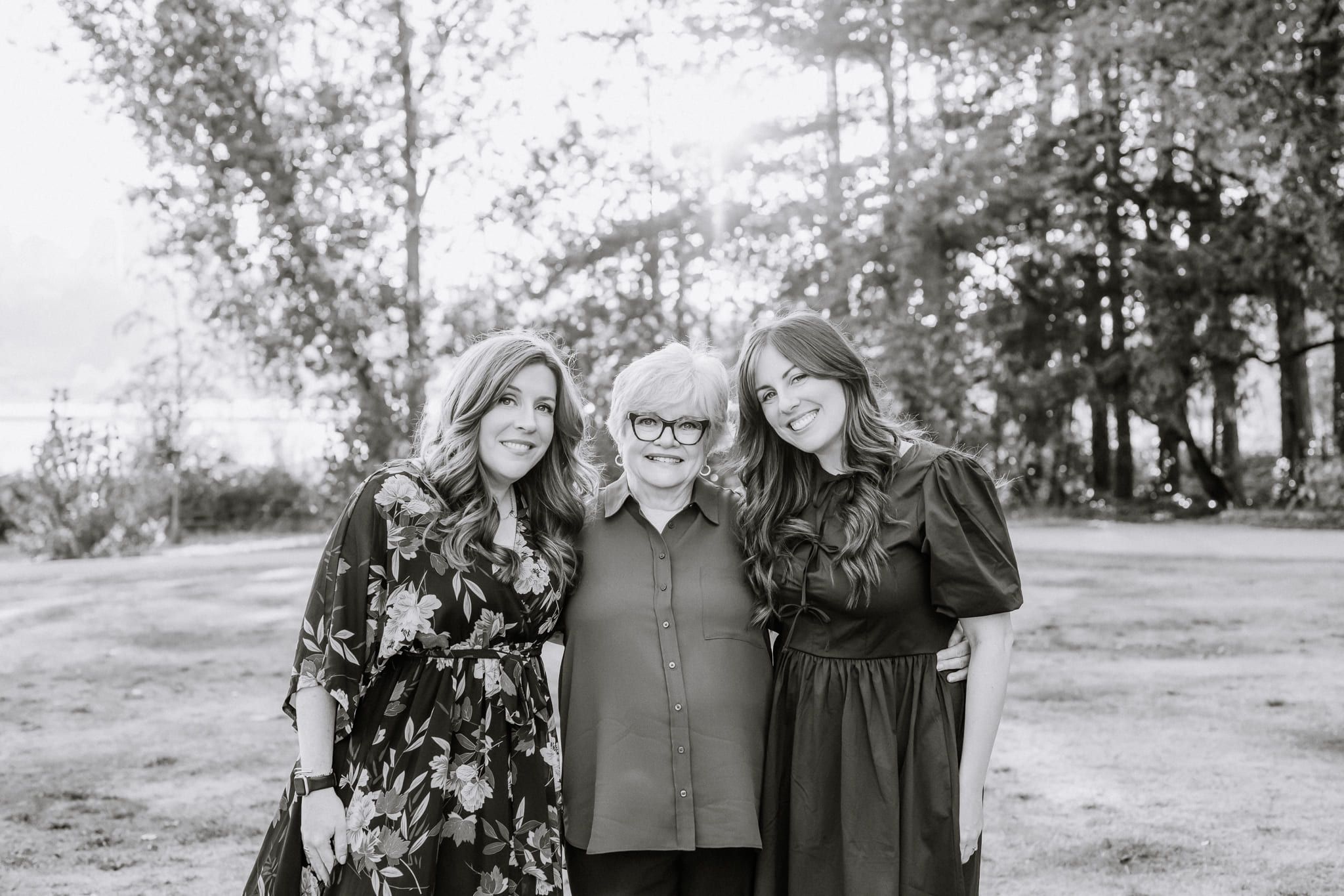 Black-and-white photo of three women of a family standing together in a park, by Port Coquitlam family photographer Natalie Varro