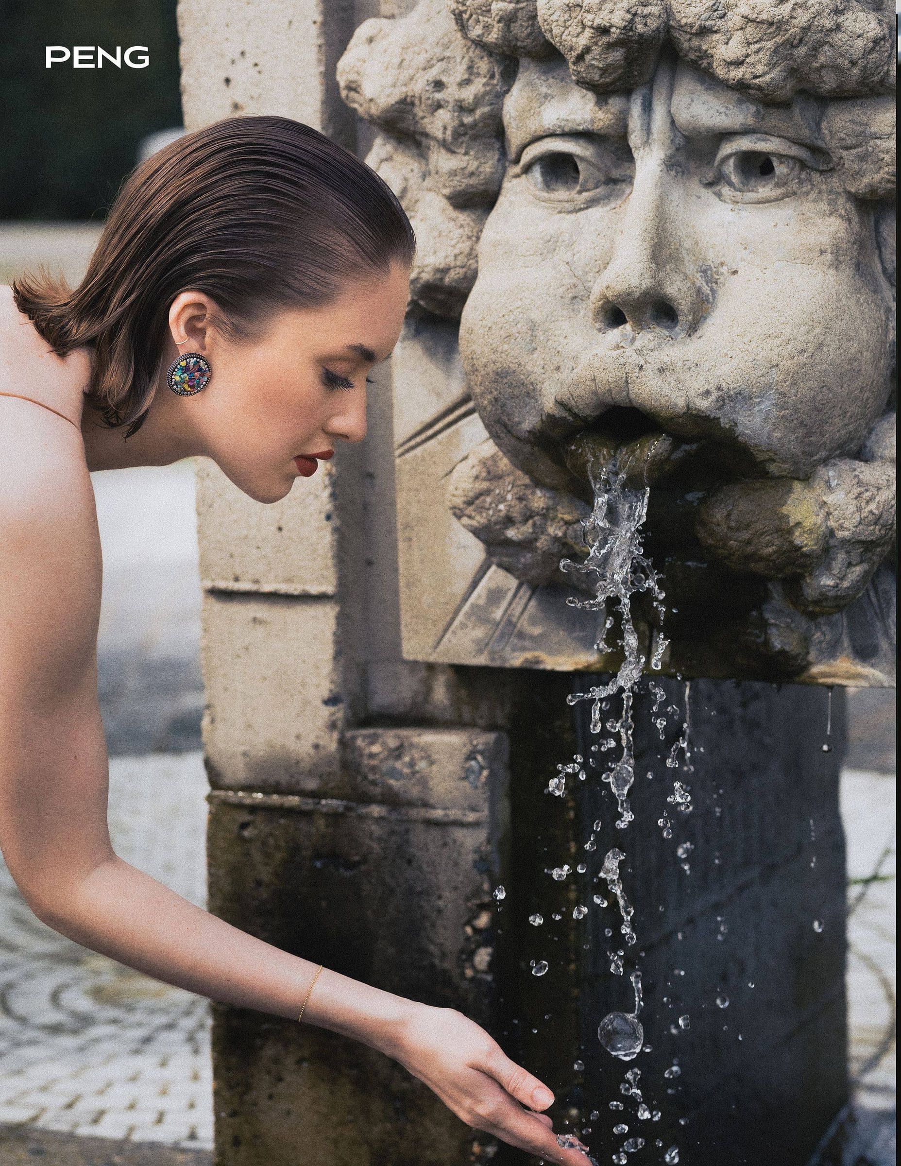Model in a silk dress touching a stone fountain, from PENG magazine