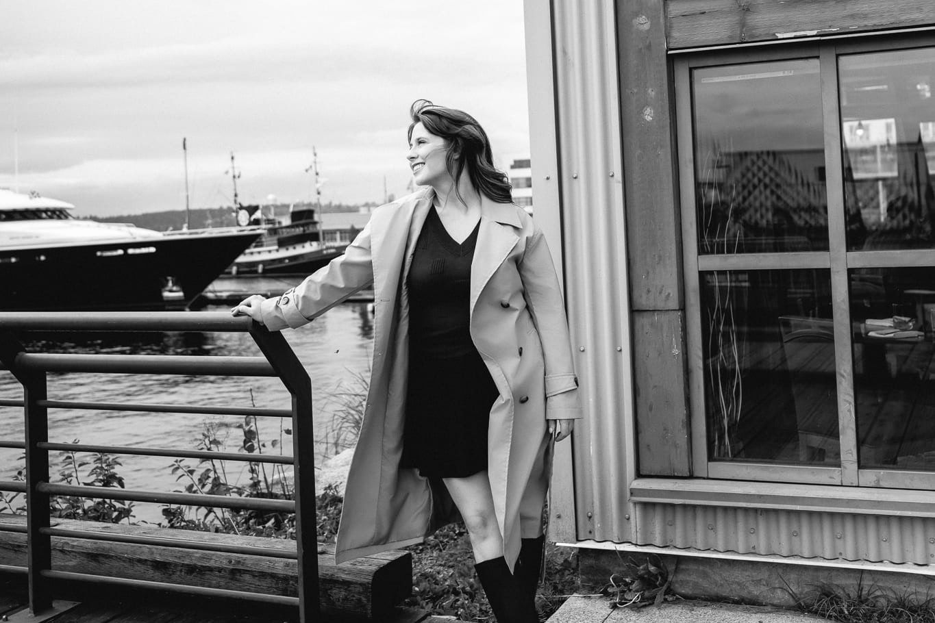 Monochrome portrait photography, woman in a long coat by the boardwalk railing, in black and white