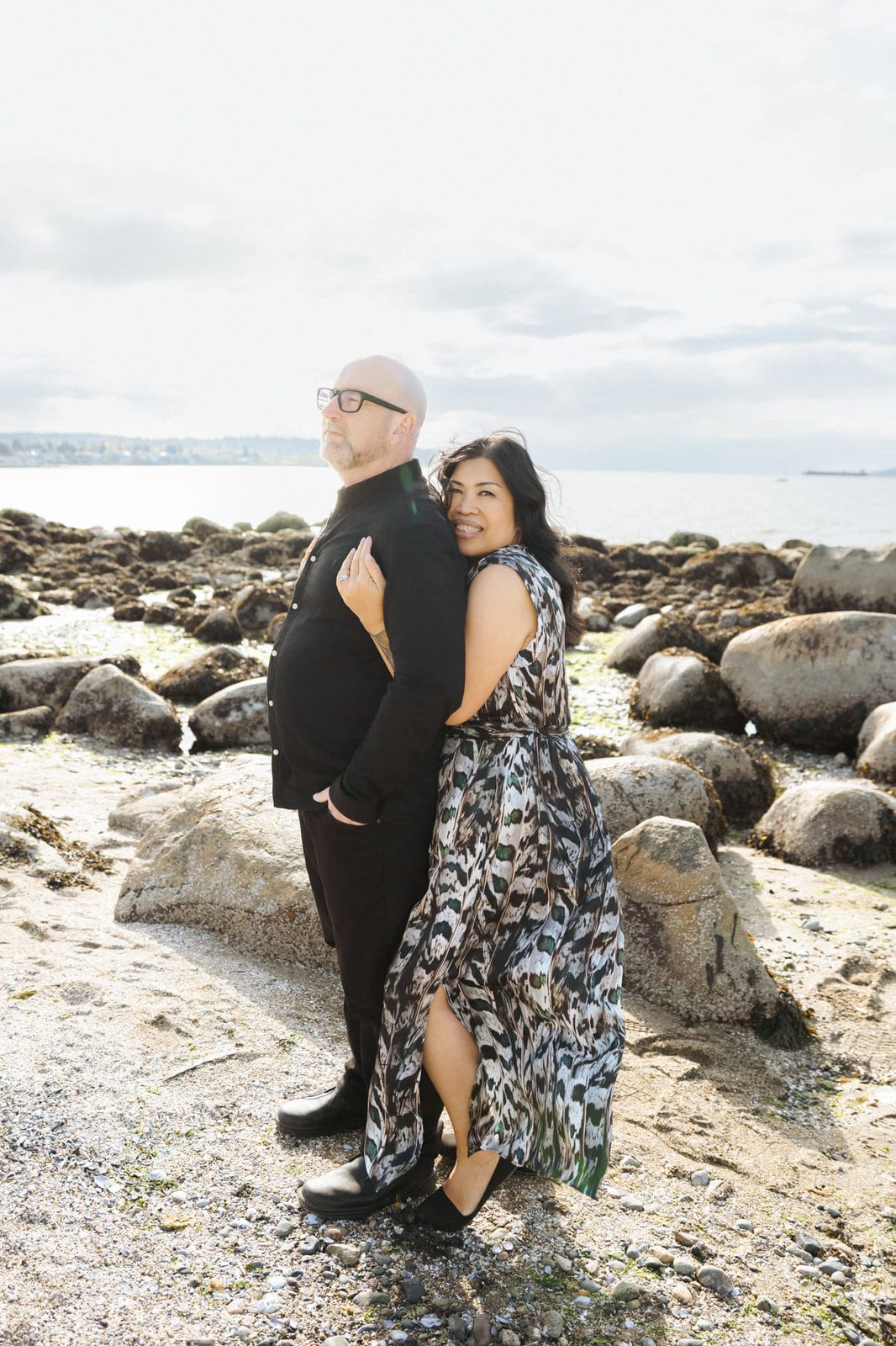 Beach engagement photos, couple standing together on rocks by the sea