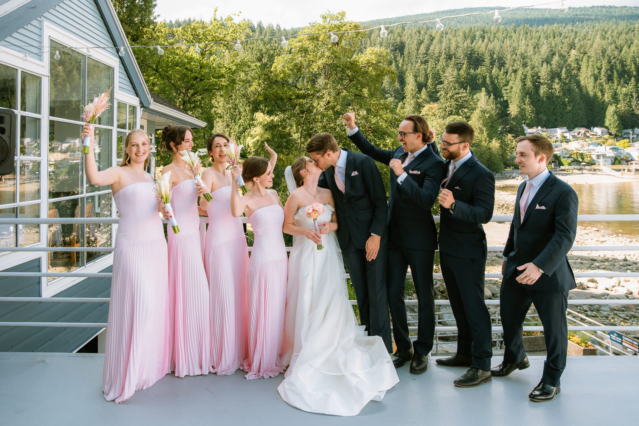 Wedding shoot, wedding party cheering on a waterfront terrace