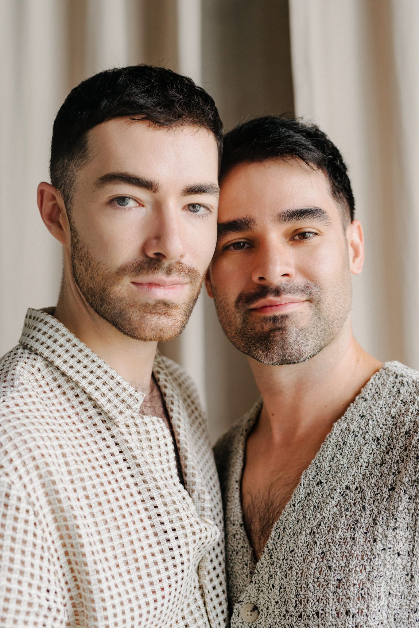 Couple studio pictures of two men posing together in a warm-toned studio