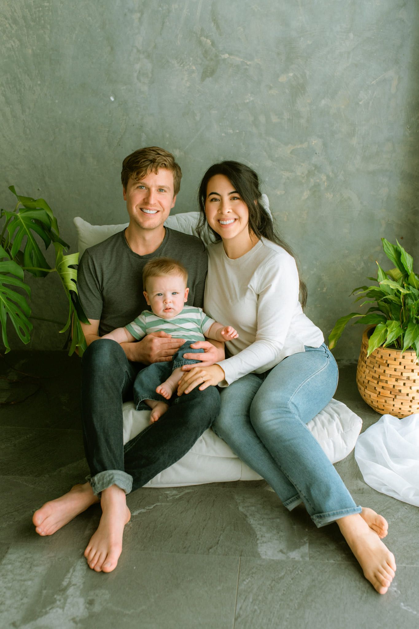 Indoor family photography in a studio, young parents with their baby sitting barefoot