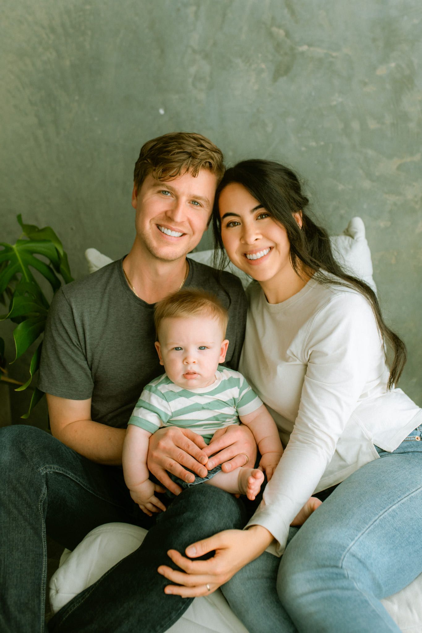 Family picture studio session, parents smiling with their baby on their laps in a studio