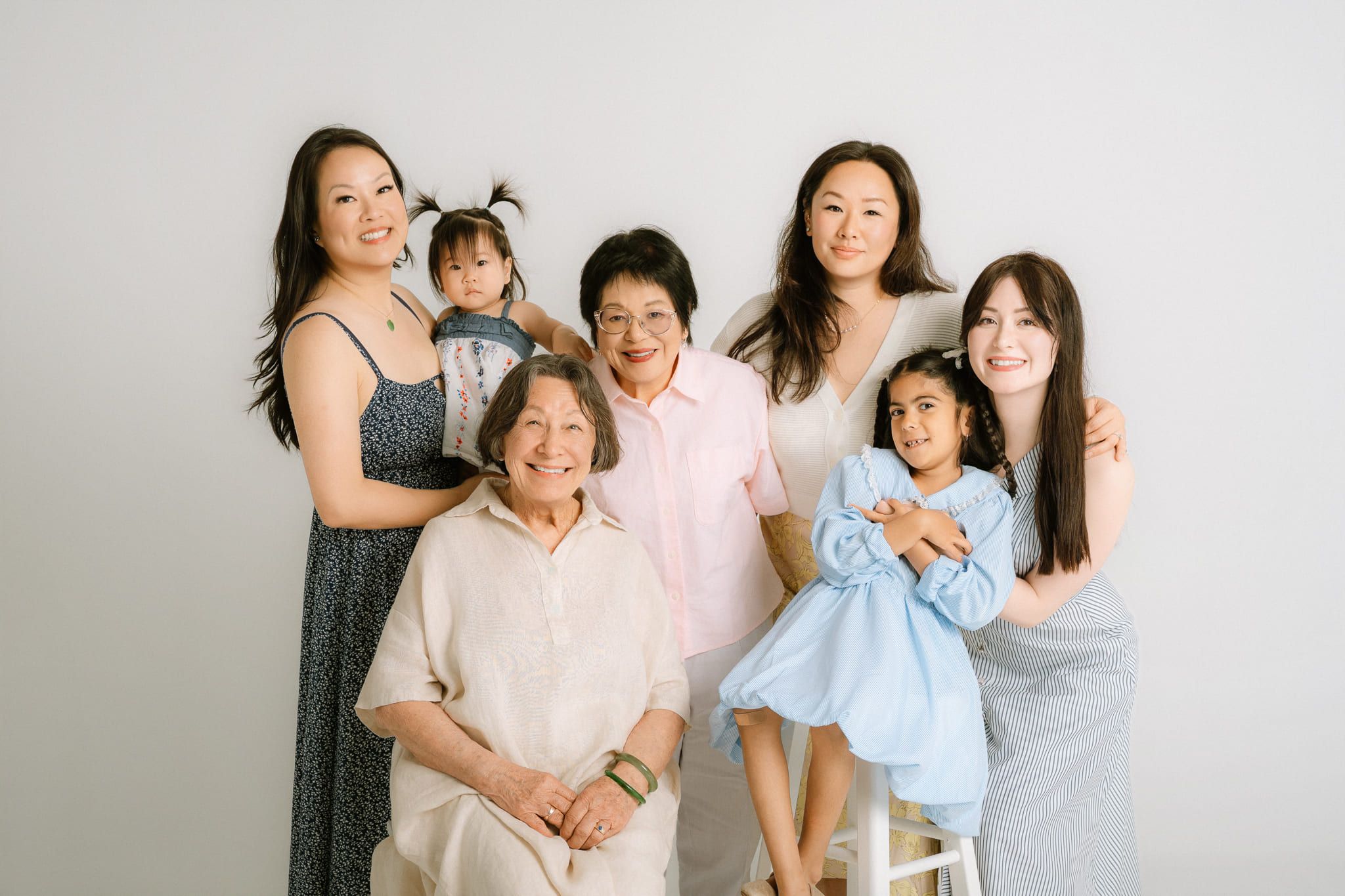 Indoor studio family photos, grandmother, mothers and little girls hugging in a white studio