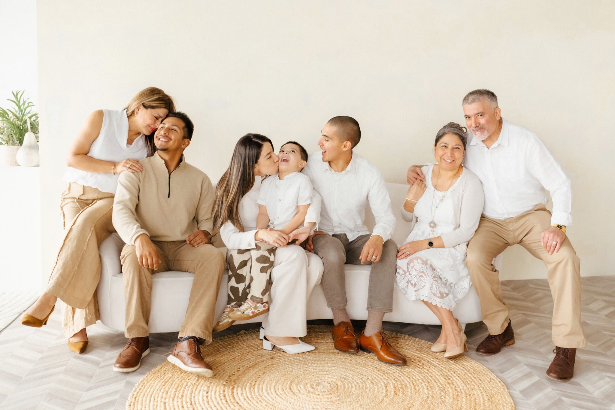 Family photos in a studio, extended family laughing on a sofa in a bright studio