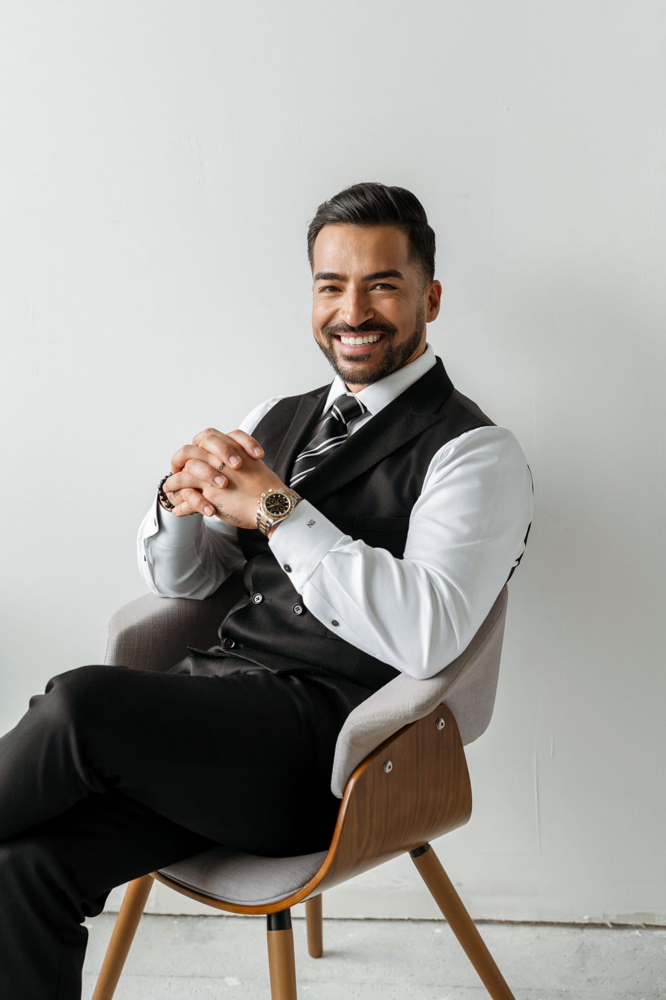 Man in a waistcoat and tie sitting on a chair in a bright studio, by Langley headshot photographer Natalie Varro