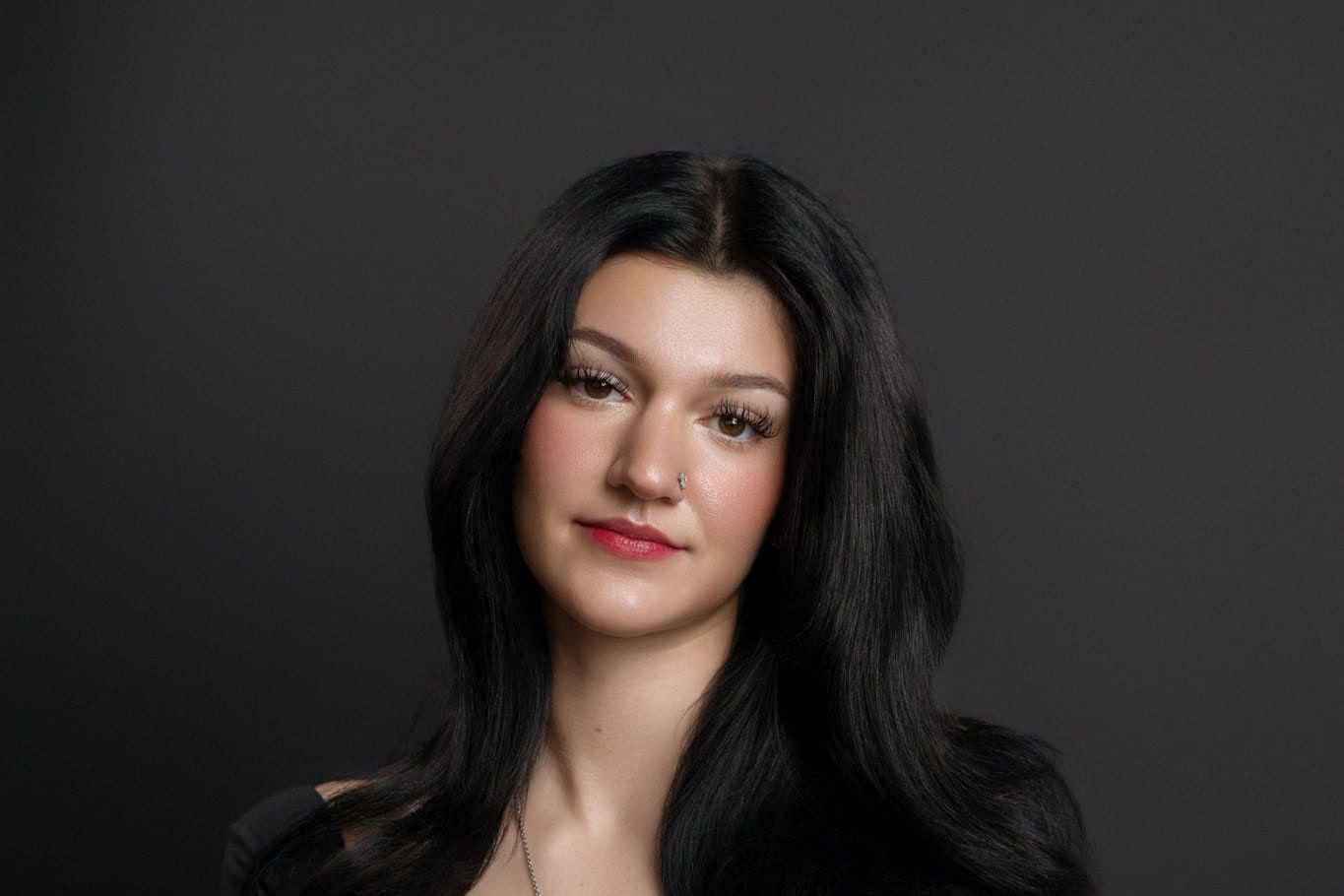 Professional corporate photography on a dark backdrop, young woman with long dark hair, a portrait