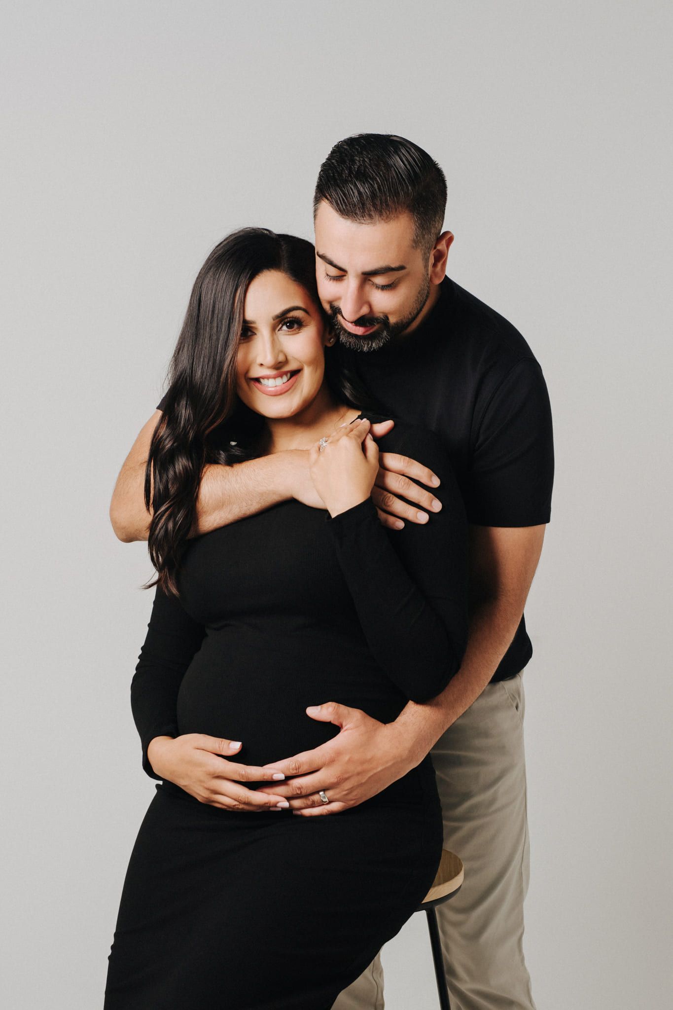 Pregnancy photoshoot in the studio, expectant couple in black in a minimalist studio