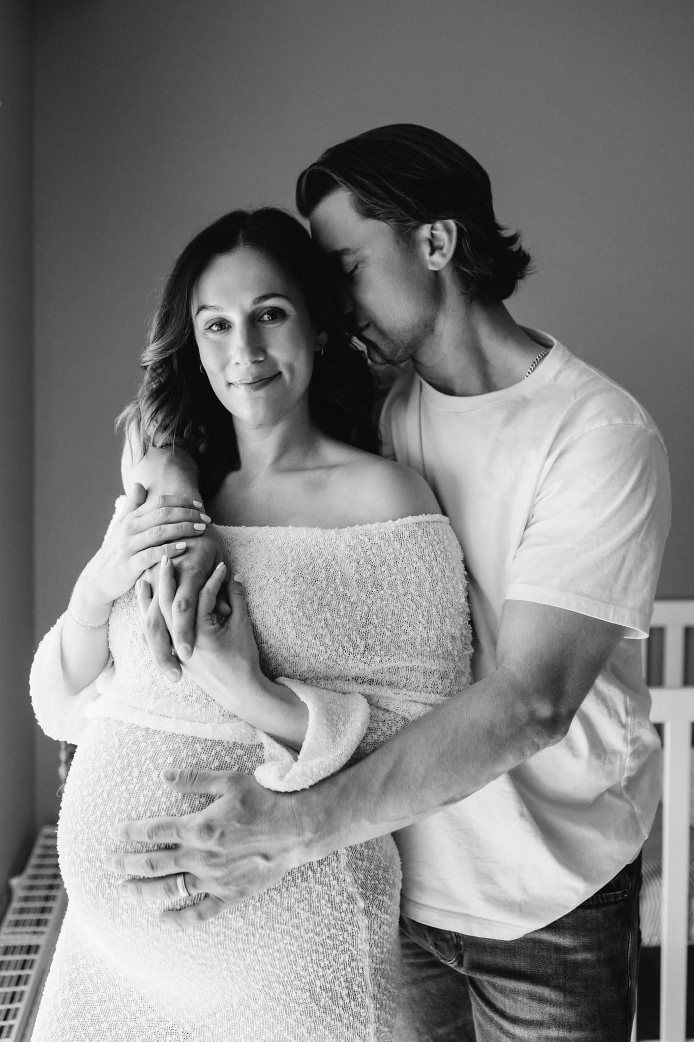 Pregnancy photos, expecting couple embracing in a studio, in black and white