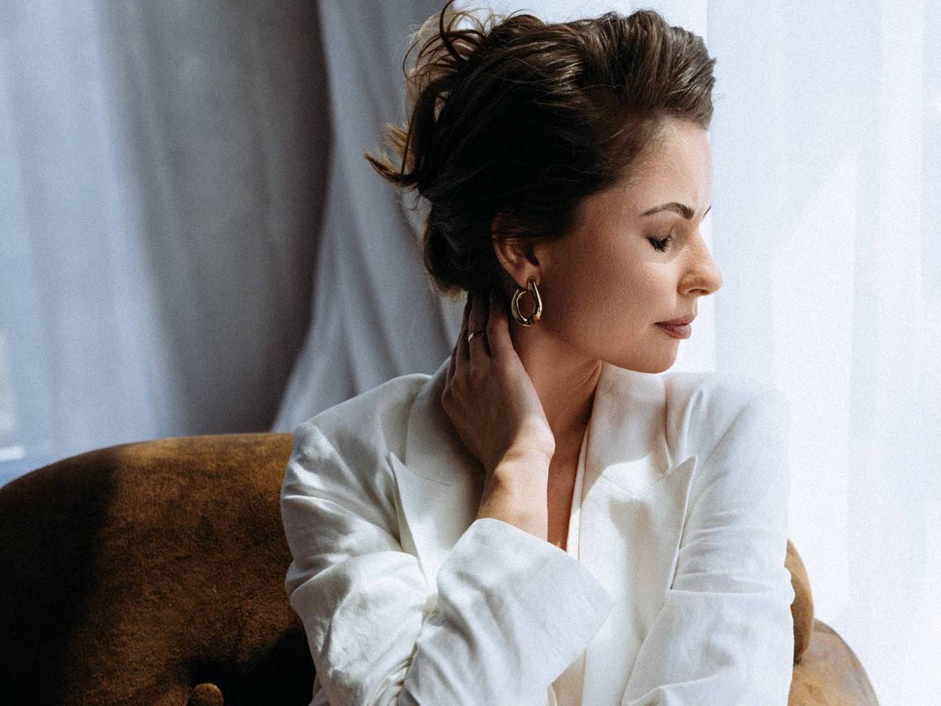 Portrait studio photoshoot, woman in a white shirt sitting by a bright window