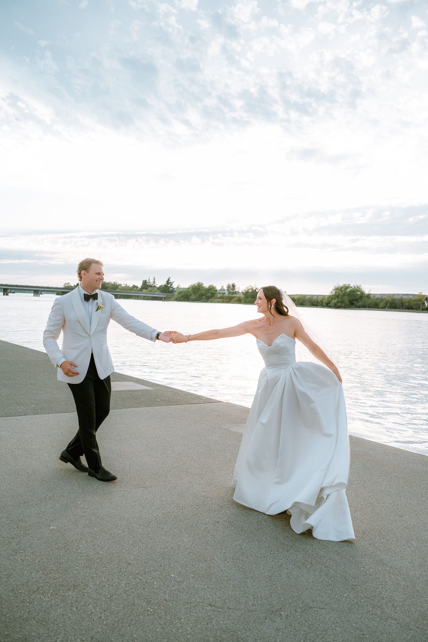 Sunset wedding photos, bride and groom dancing on a waterfront path