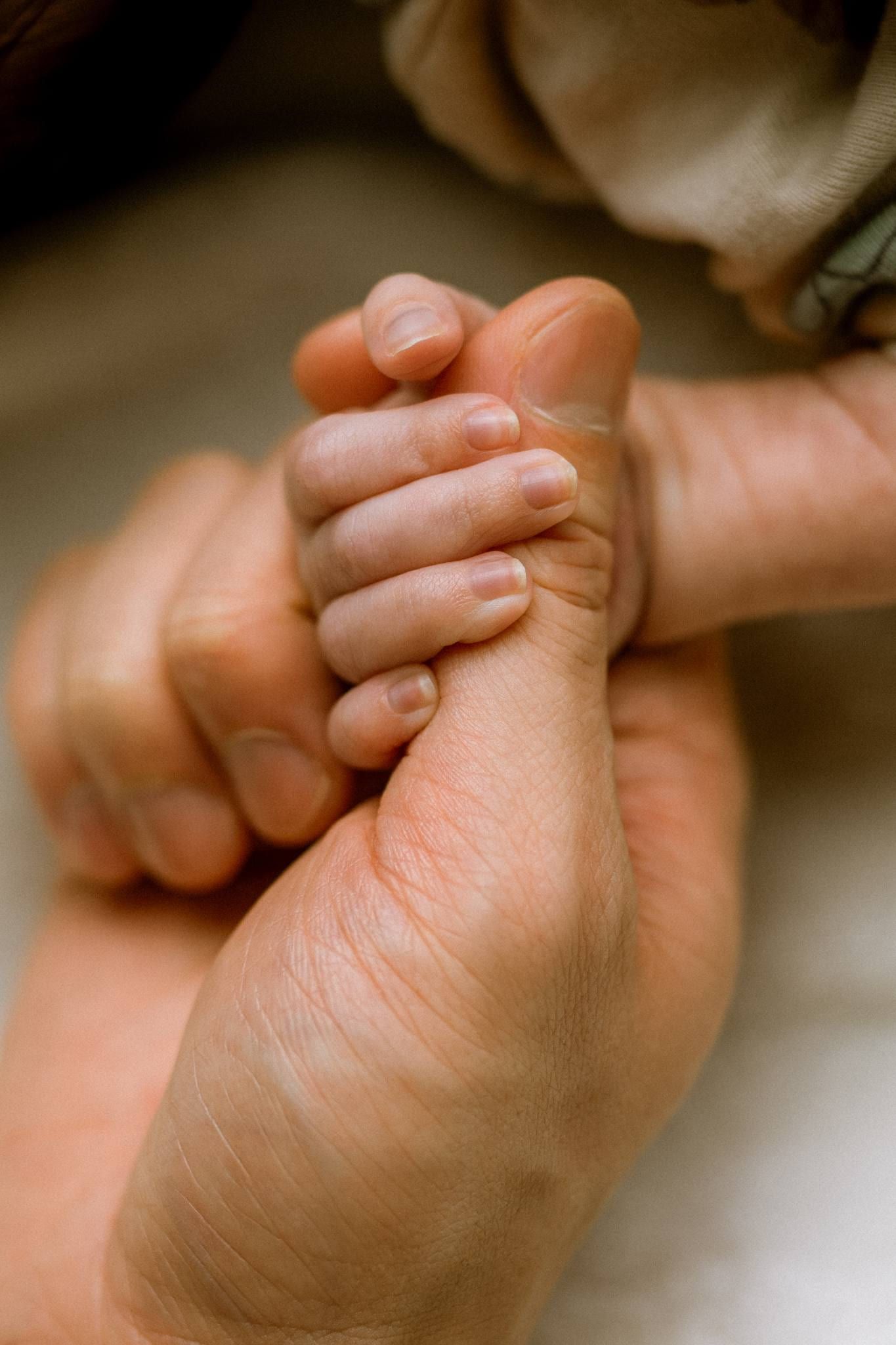 Newborn hand gripping a parent's finger