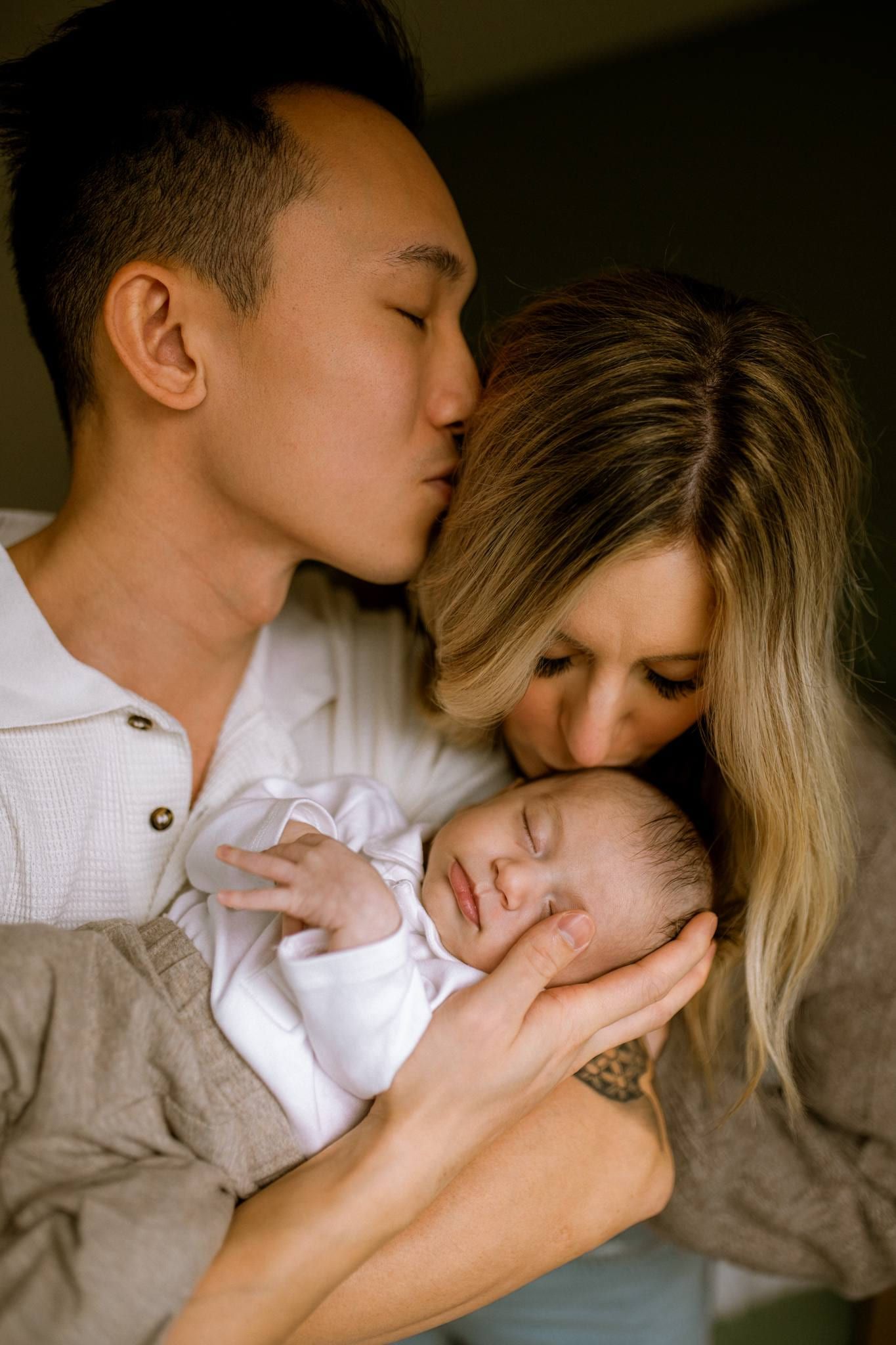 Parents cradling their sleeping newborn between them