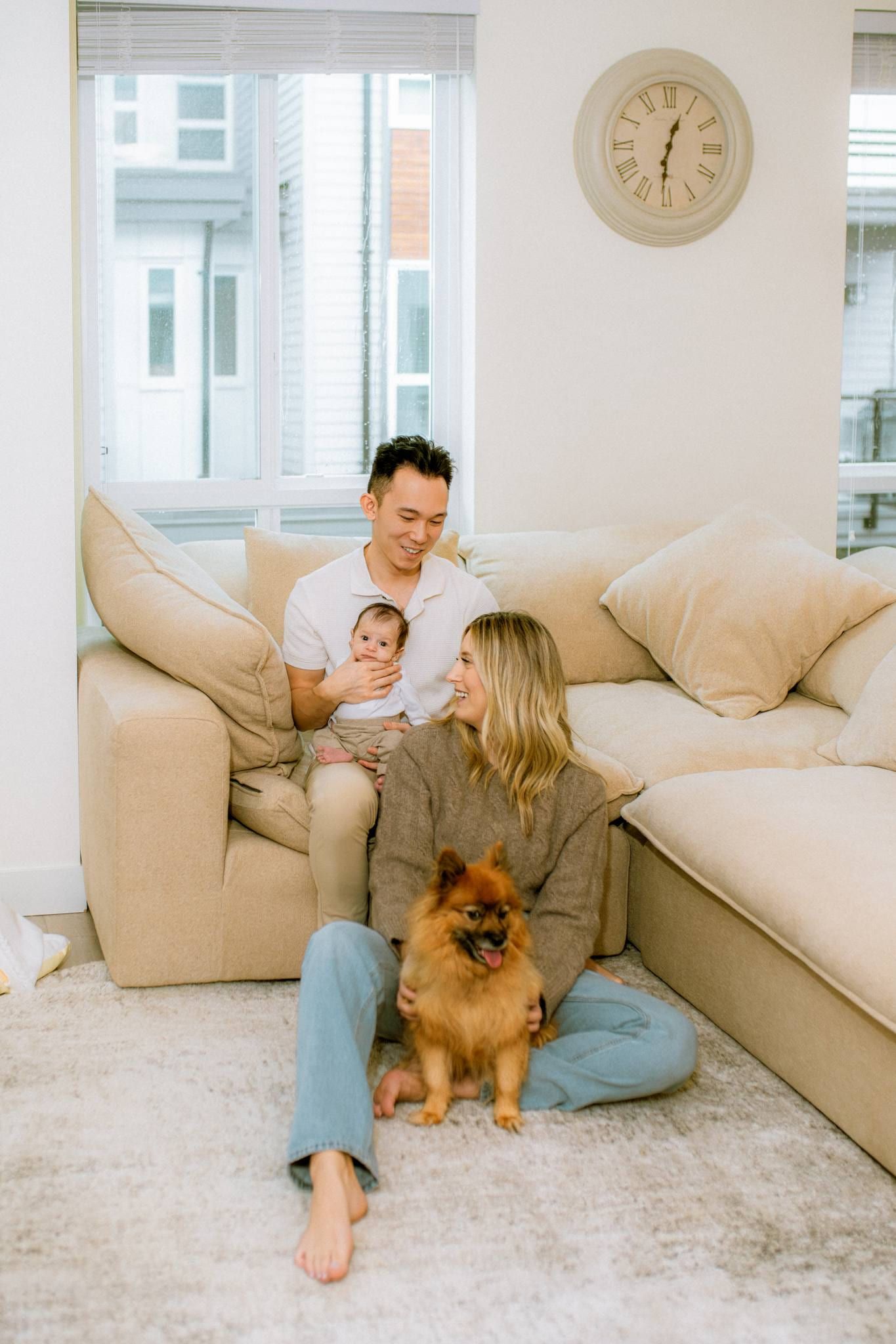 Family of three with their dog on a sofa in a bright living room