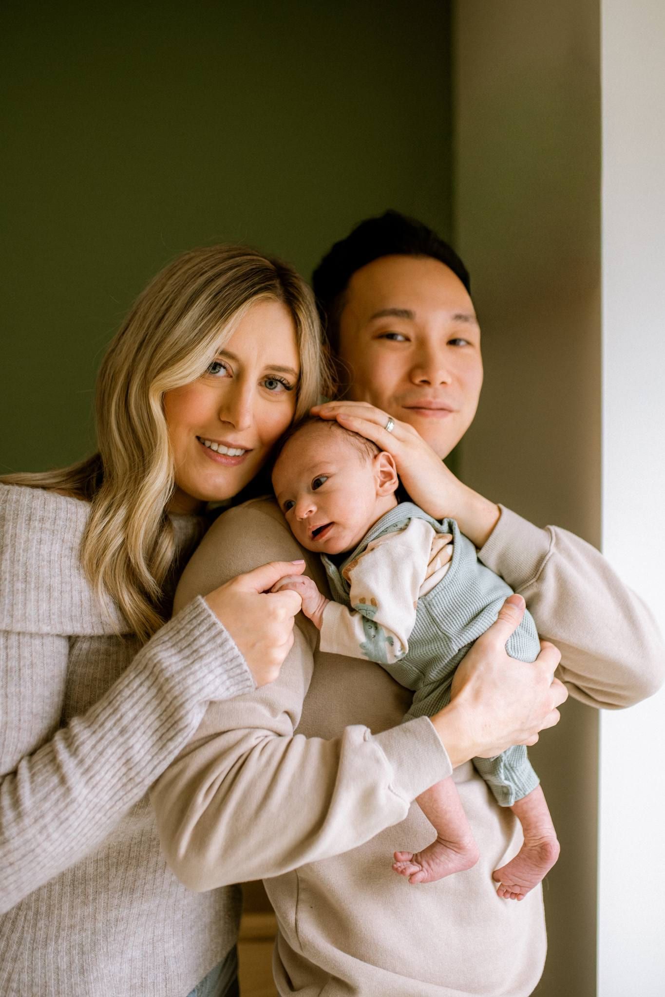Parents smiling as they cradle their newborn between them