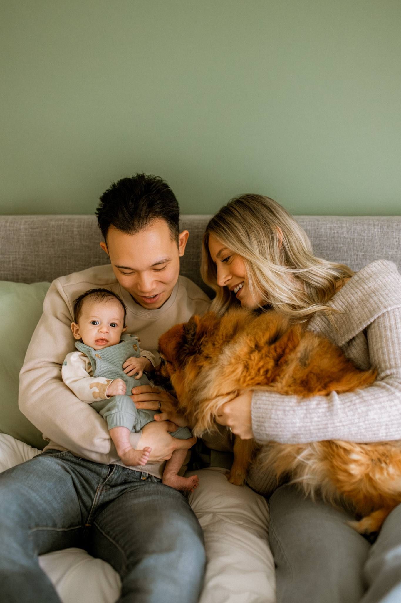 Parents on a sofa with their newborn and golden retriever
