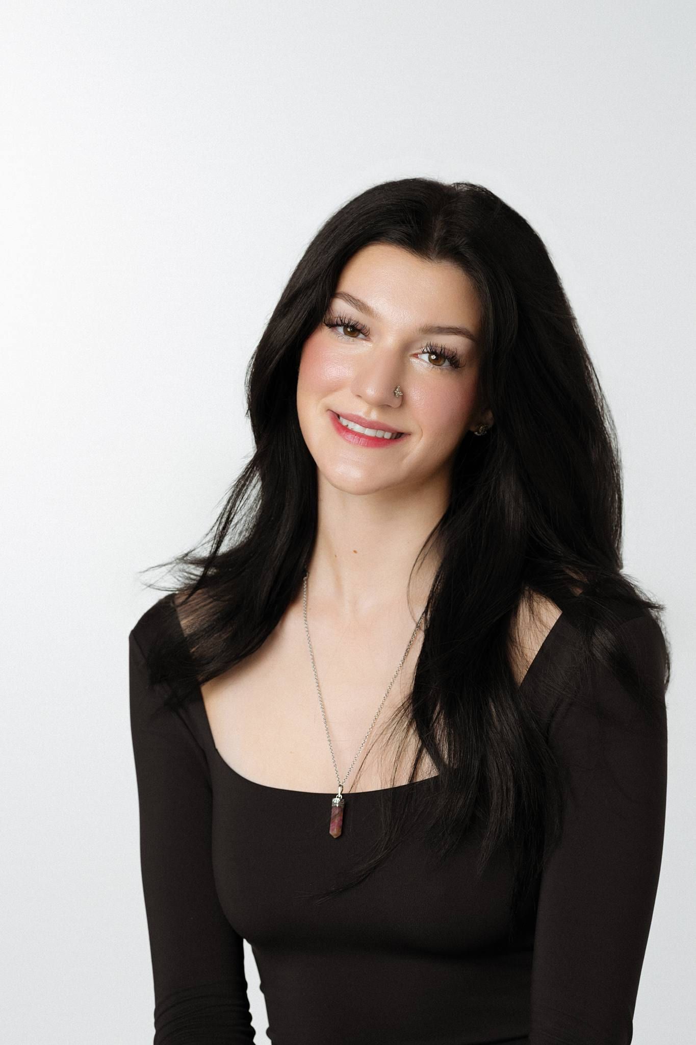 Woman in a black top smiling on a white backdrop