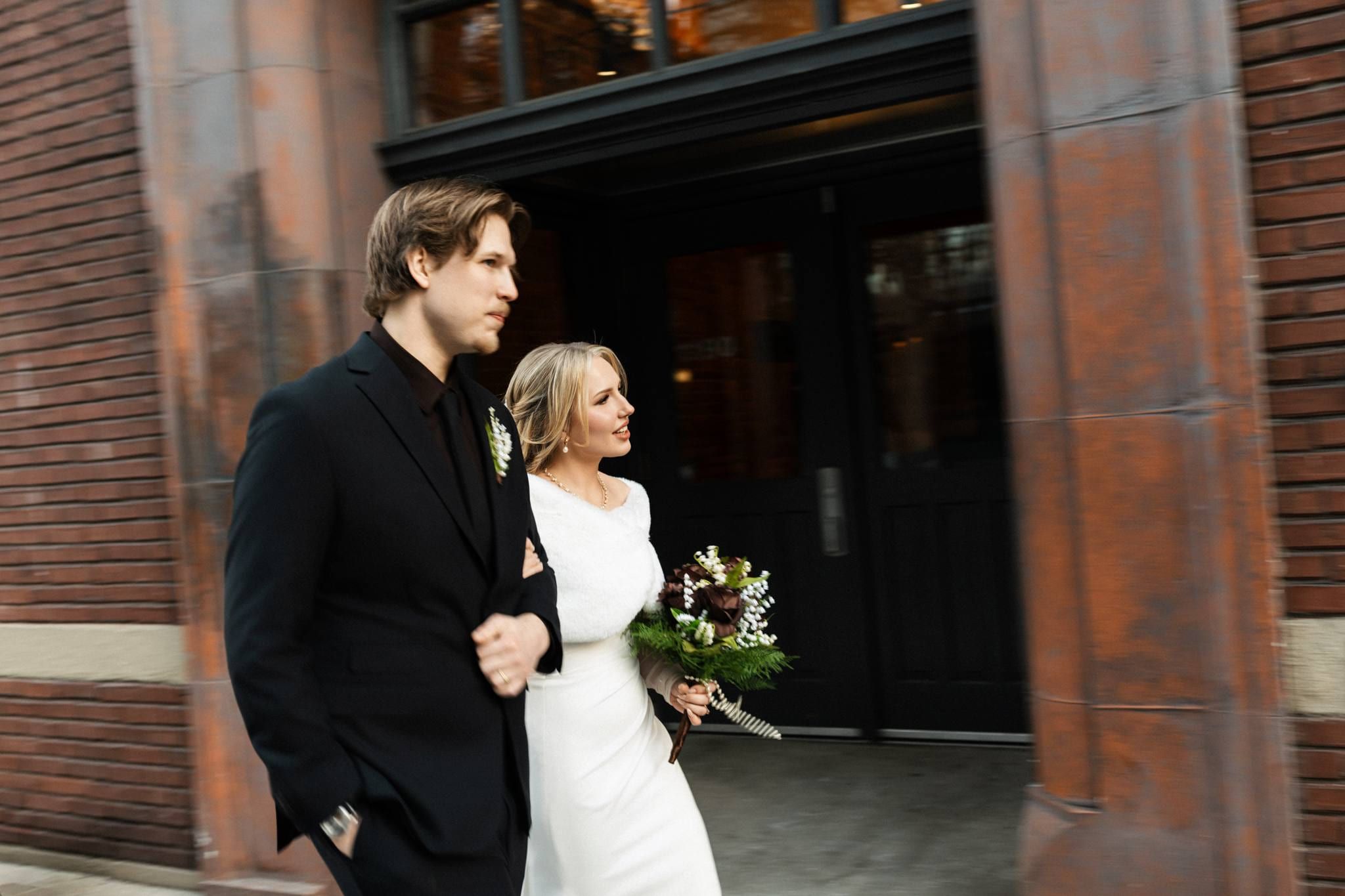 Couple walking hand in hand past a red brick wall