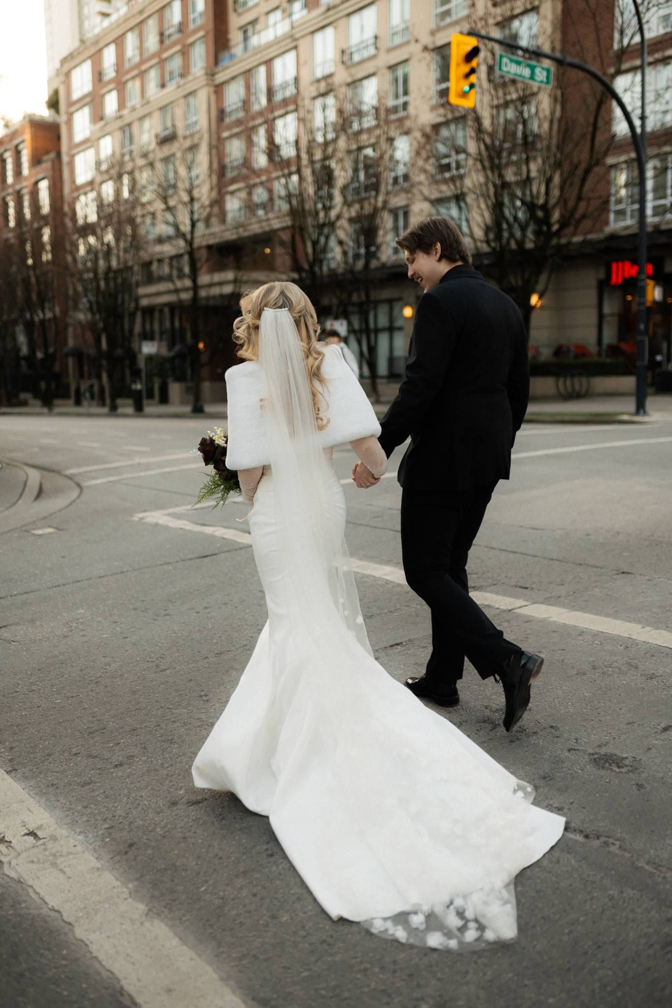 Couple crossing the downtown street, her train sweeping behind