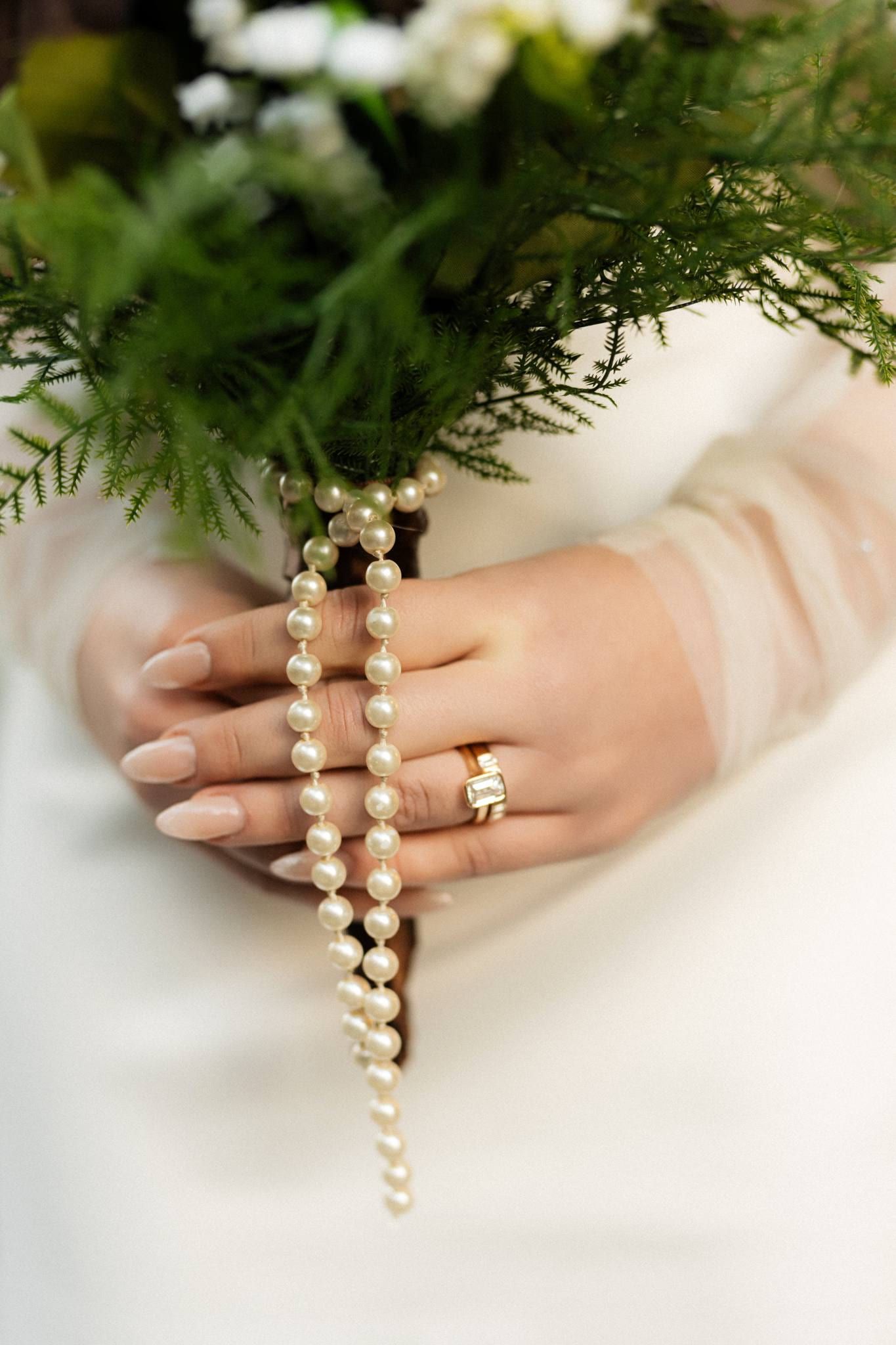 Close-up of the bride's ring hand and pearl bracelet