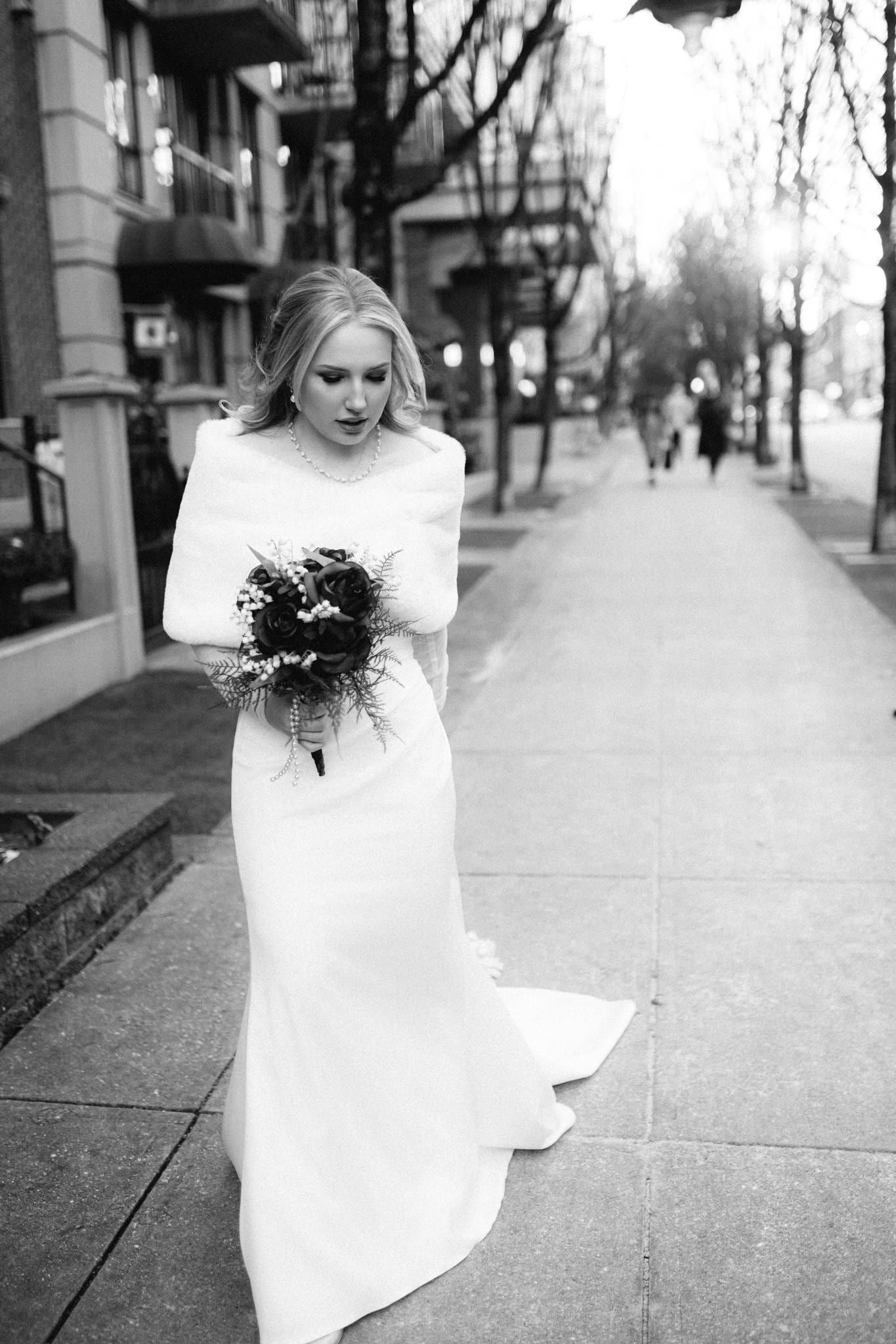 Black-and-white photo of the bride walking down a city sidewalk