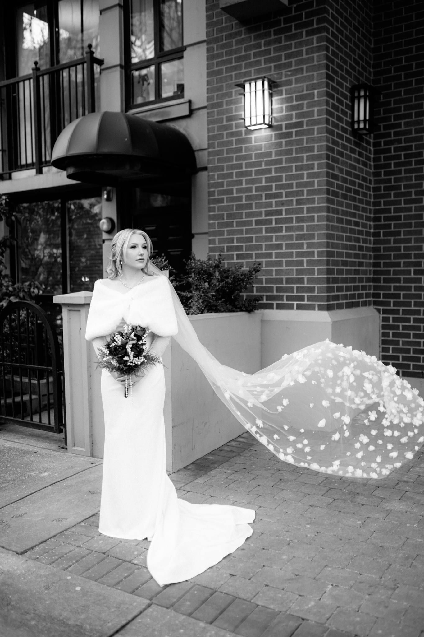 Black-and-white photo of the bride walking away with her veil trailing