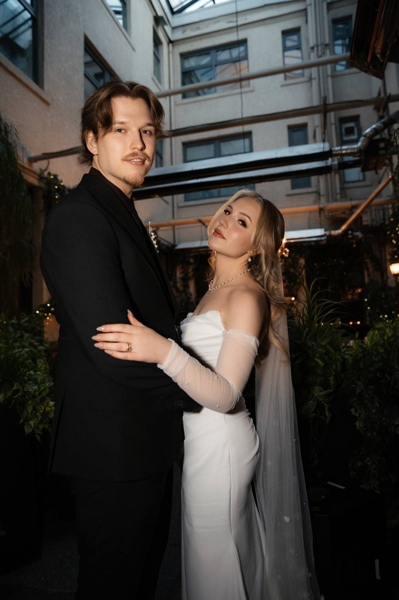 Bride and groom embracing under a street lamp in the courtyard