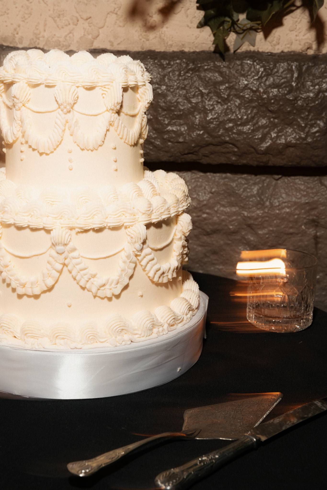 Tiered white wedding cake with piped garlands, close up