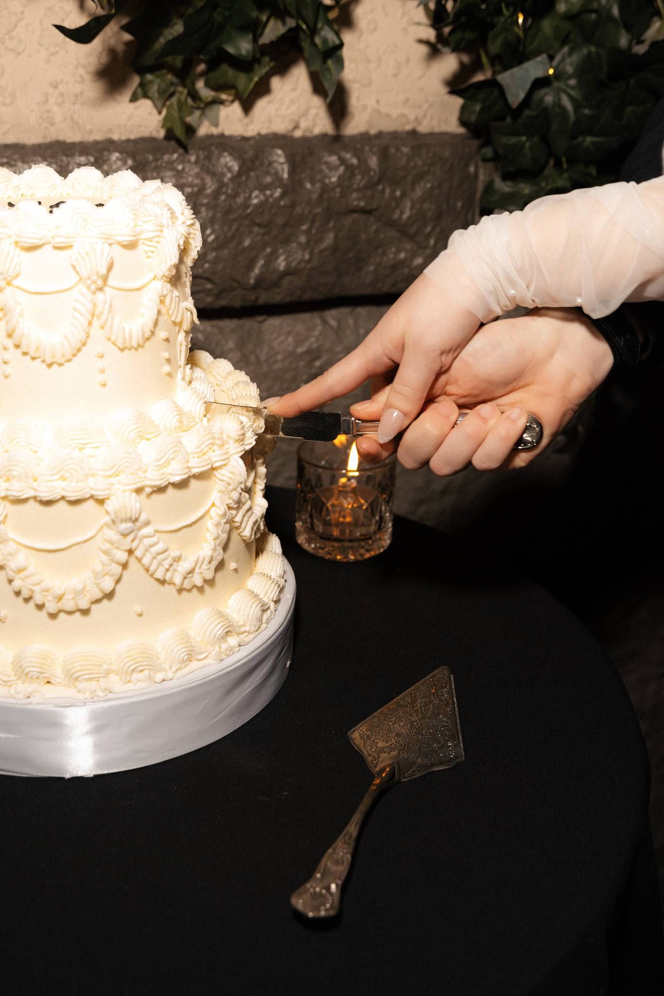 Hand cutting a slice from the tiered wedding cake