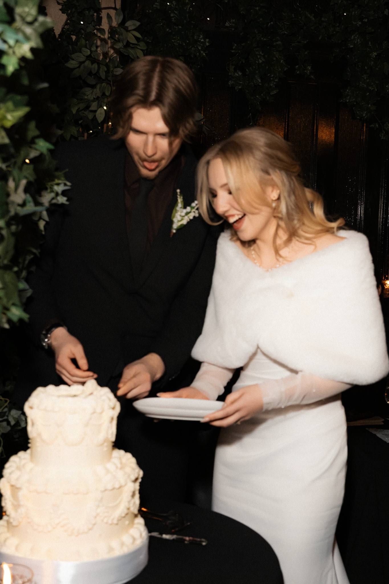 Couple laughing as they cut the cake together