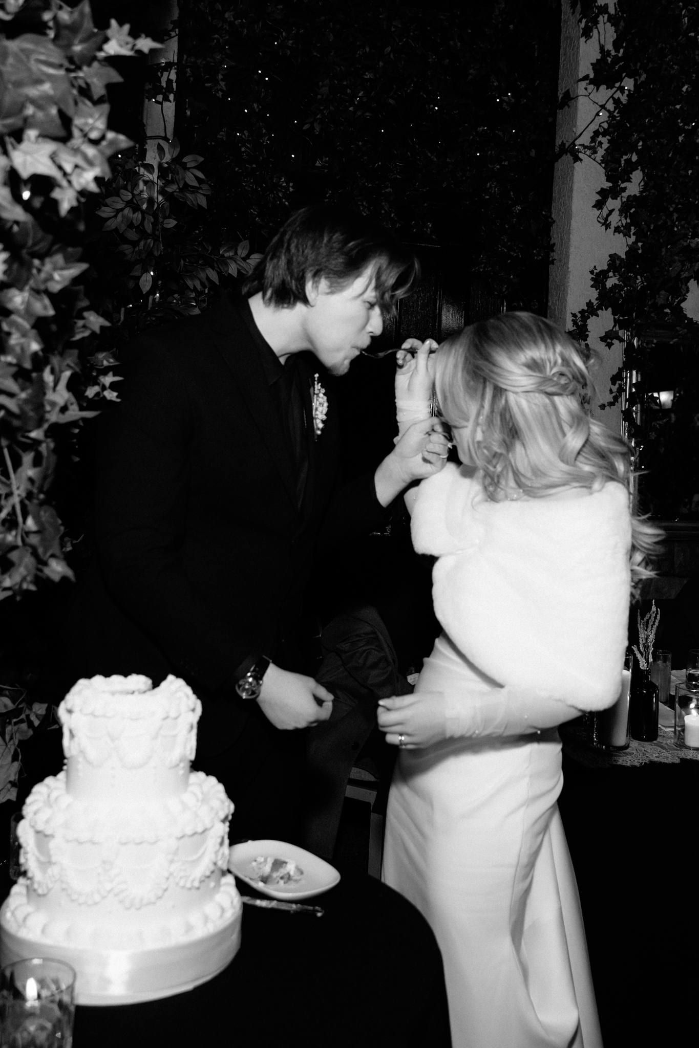 Black-and-white photo of the couple cutting their tiered cake