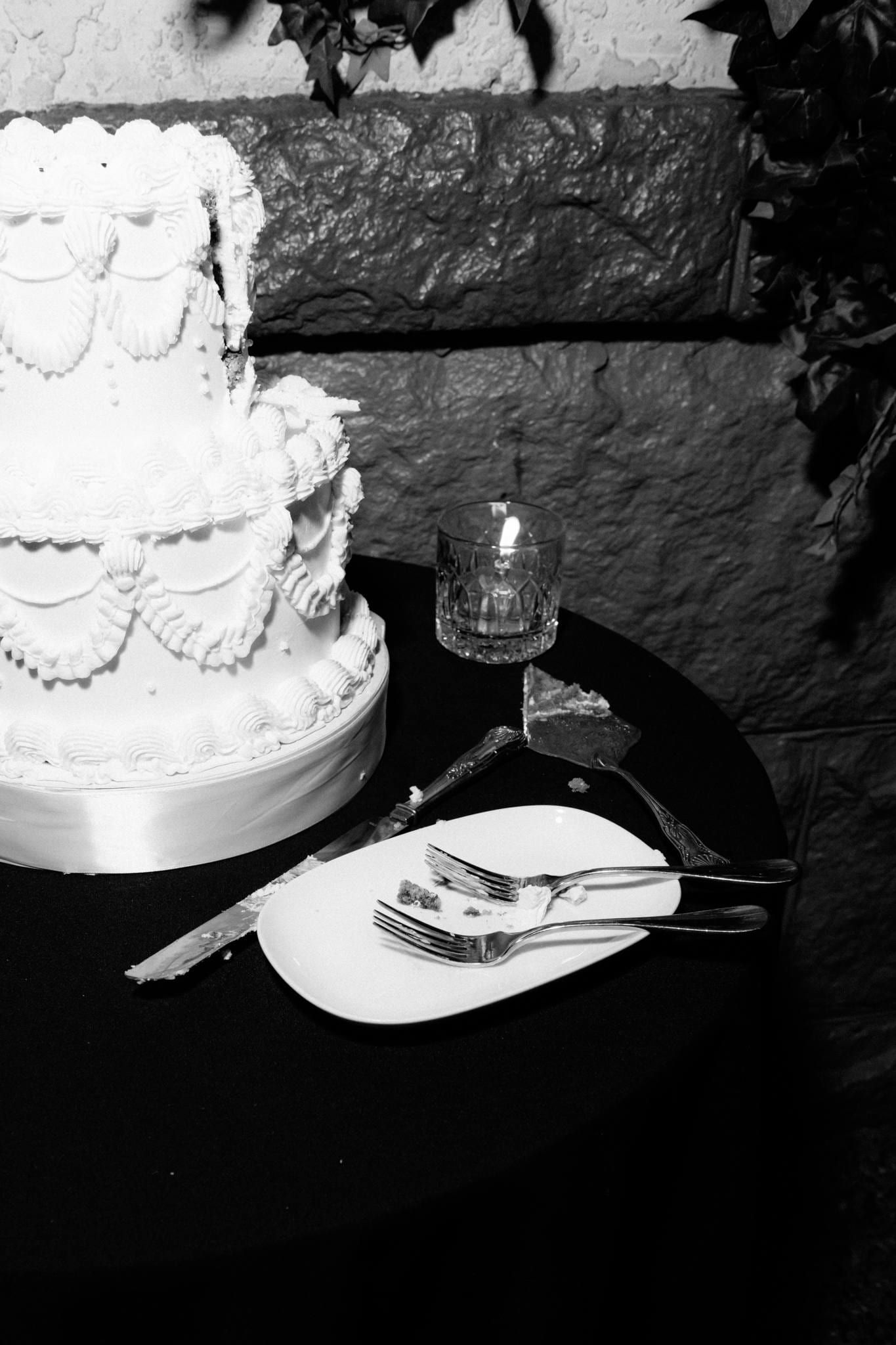Black-and-white photo of the tiered wedding cake beside a plate and forks