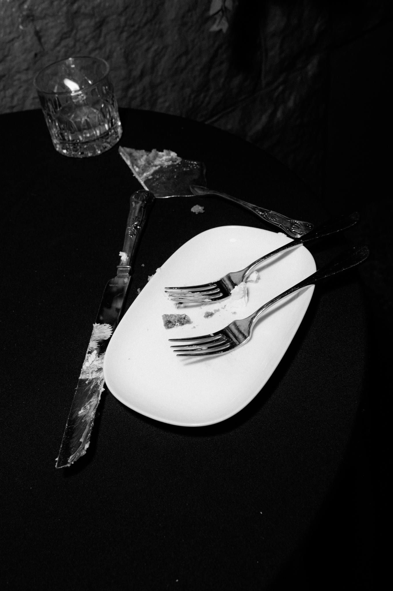 Black-and-white close-up of forks resting on a white plate