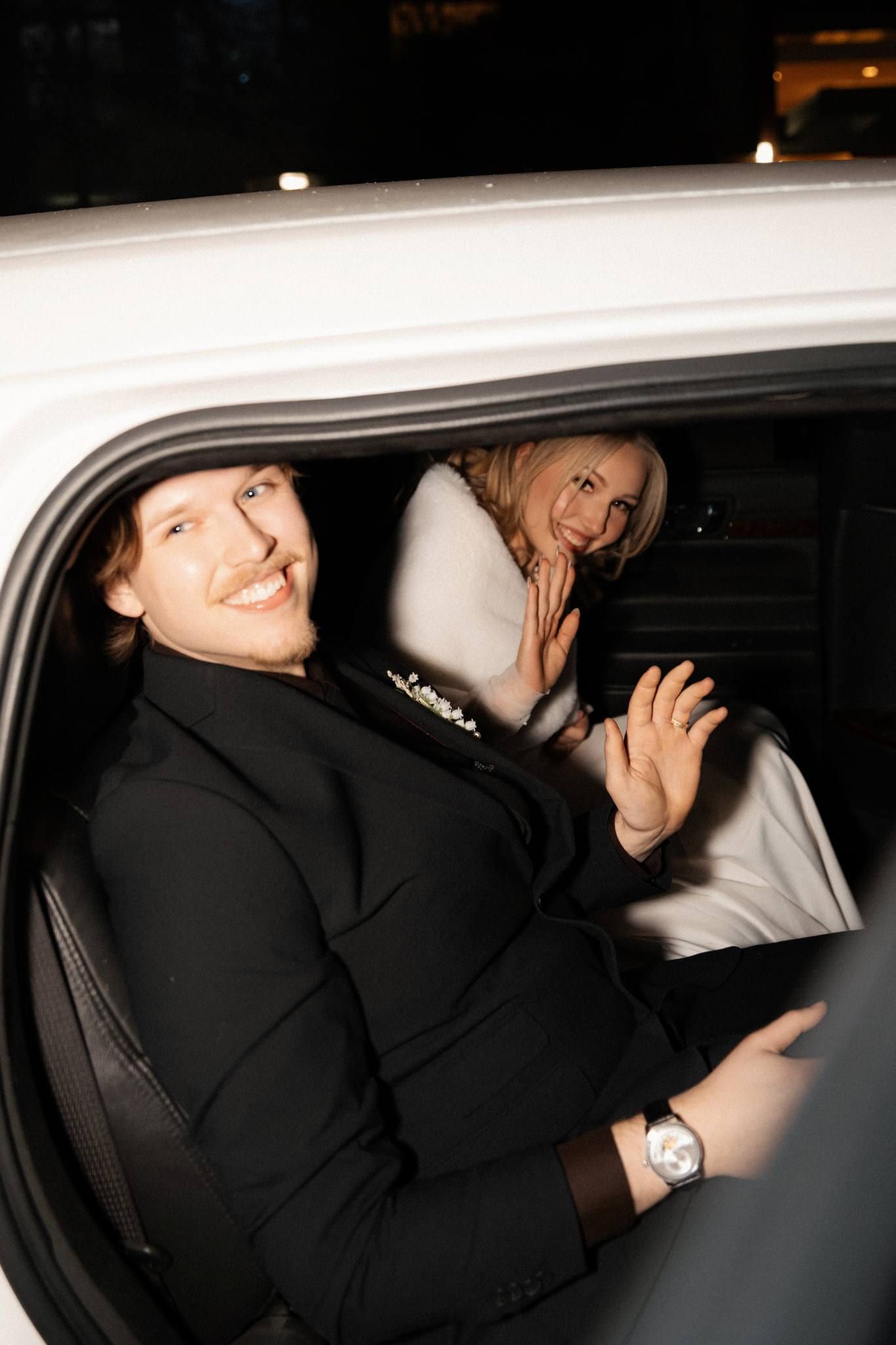 Couple peering out of the window of a black car
