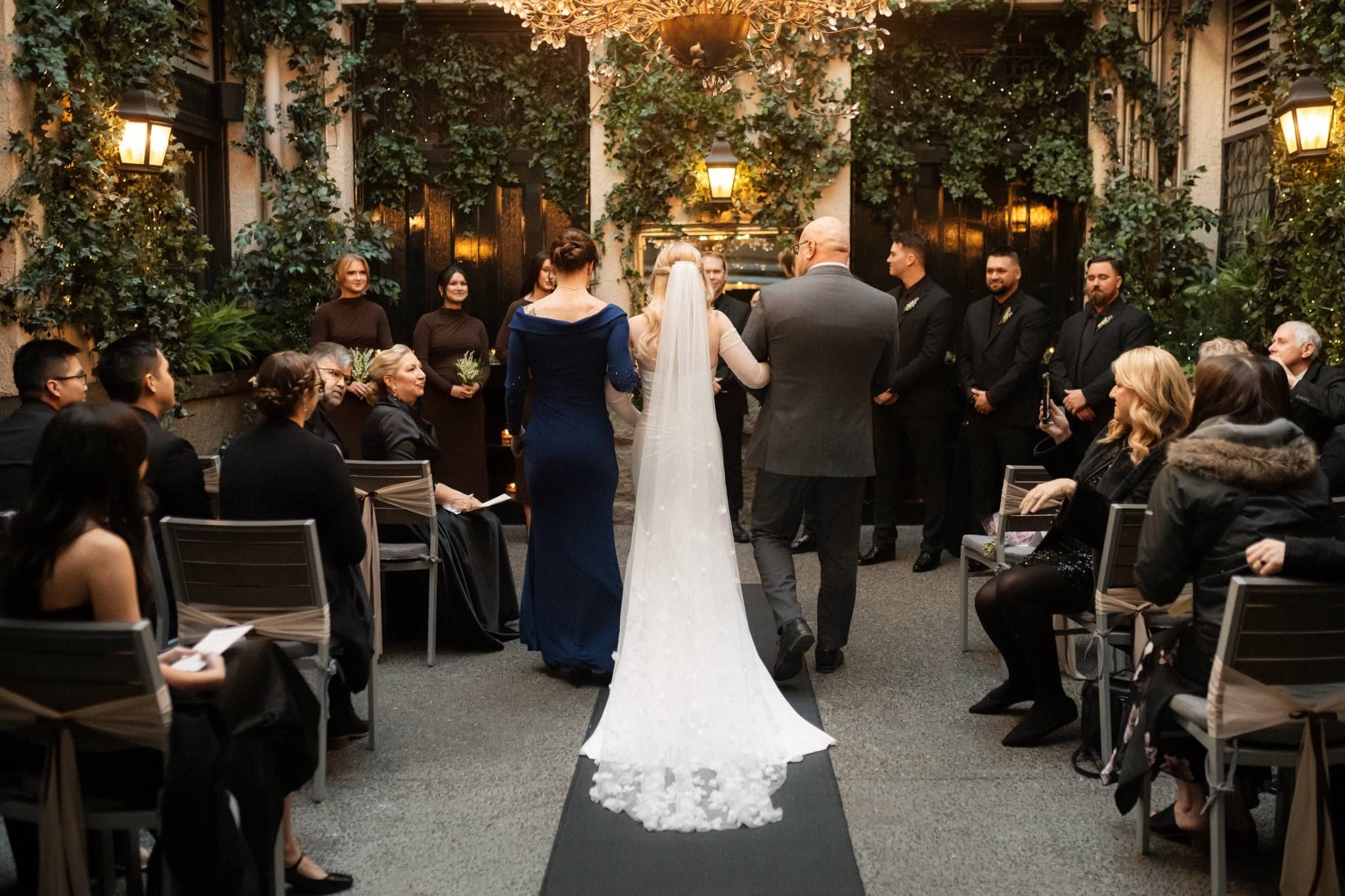 Bride walking down the aisle with her father past seated guests