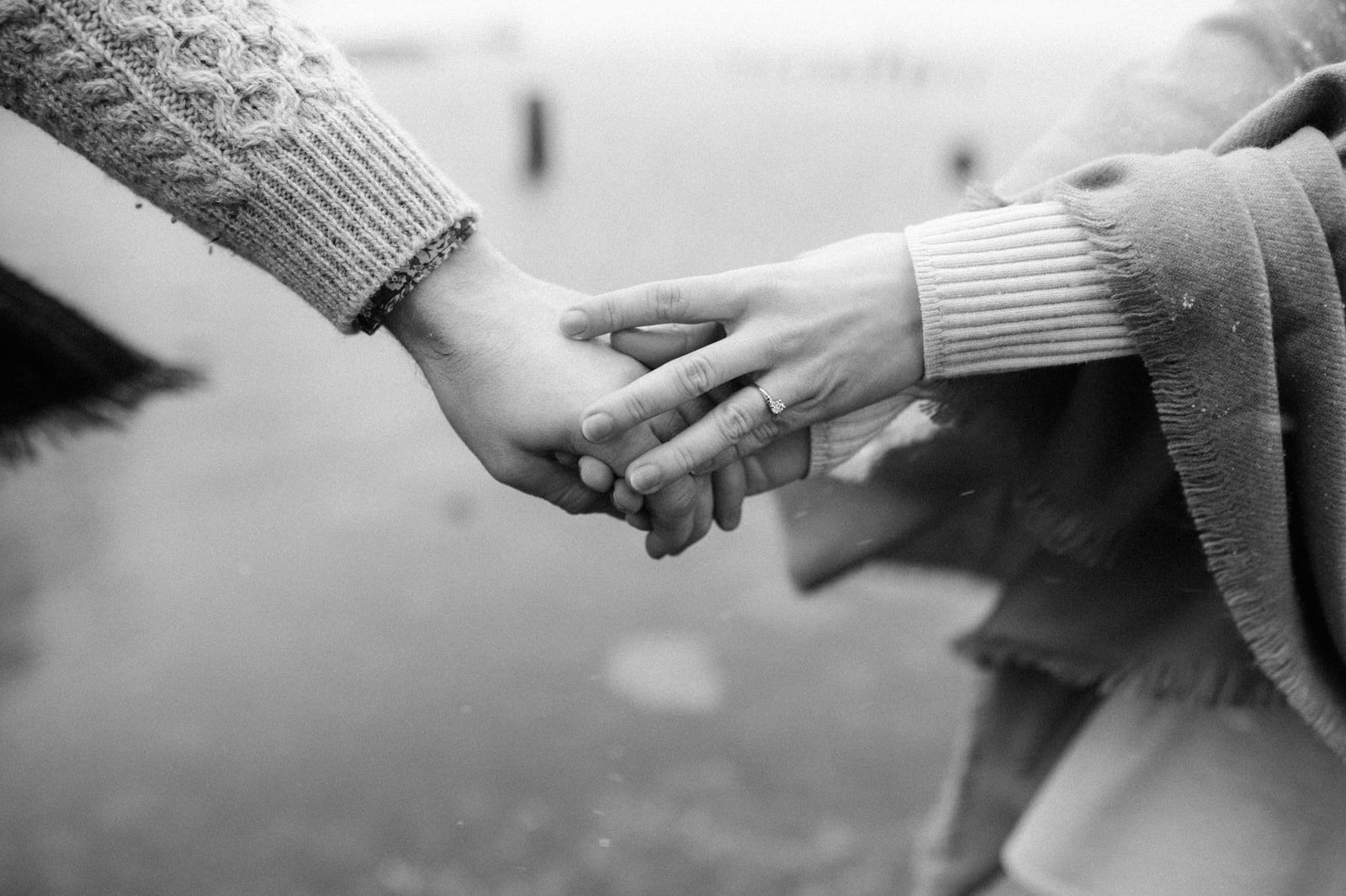 Black and white engagement pictures, hands with an engagement ring by the water