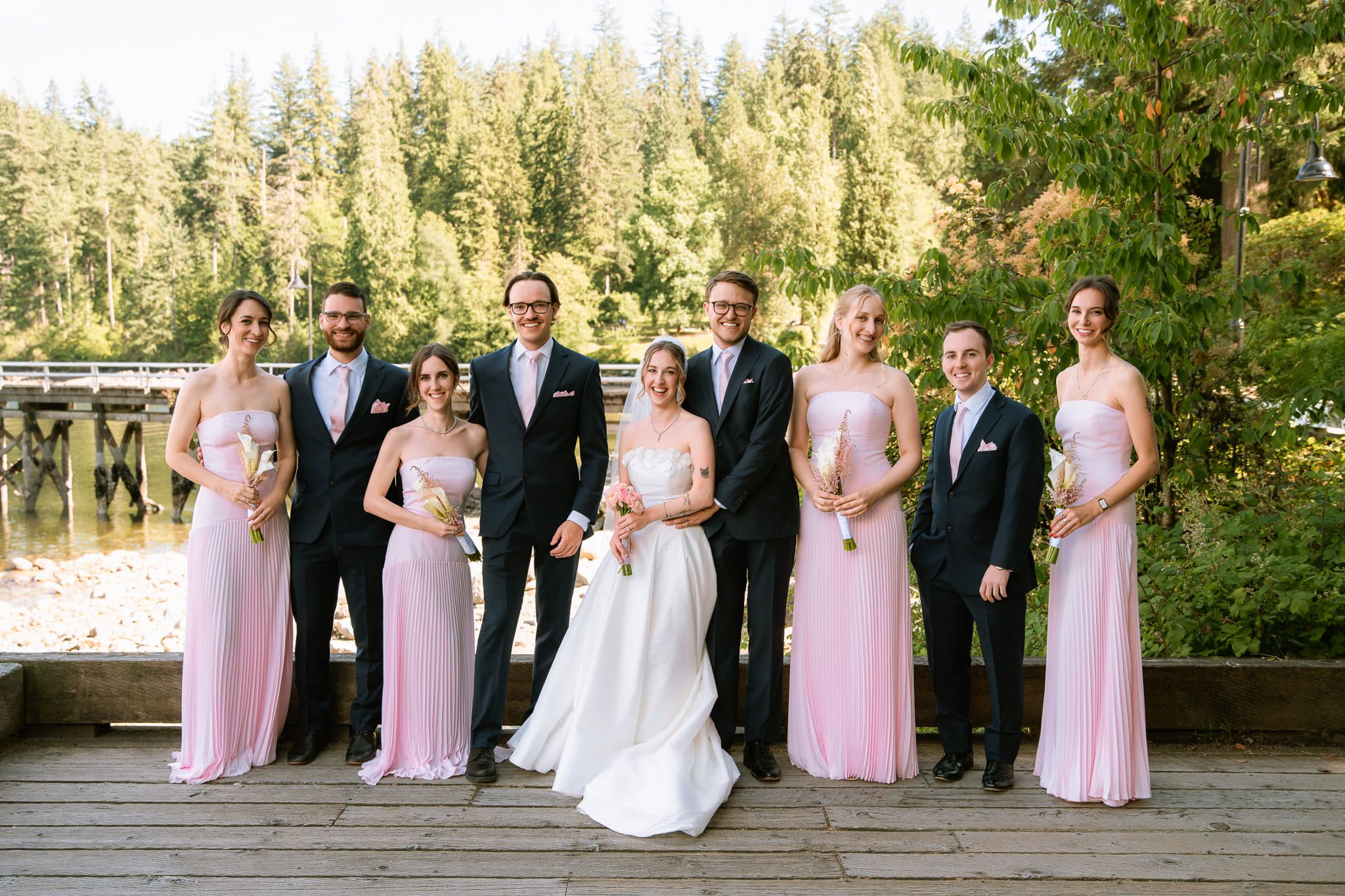 Wedding photos on a wooden deck by the water, wedding party in pink and navy