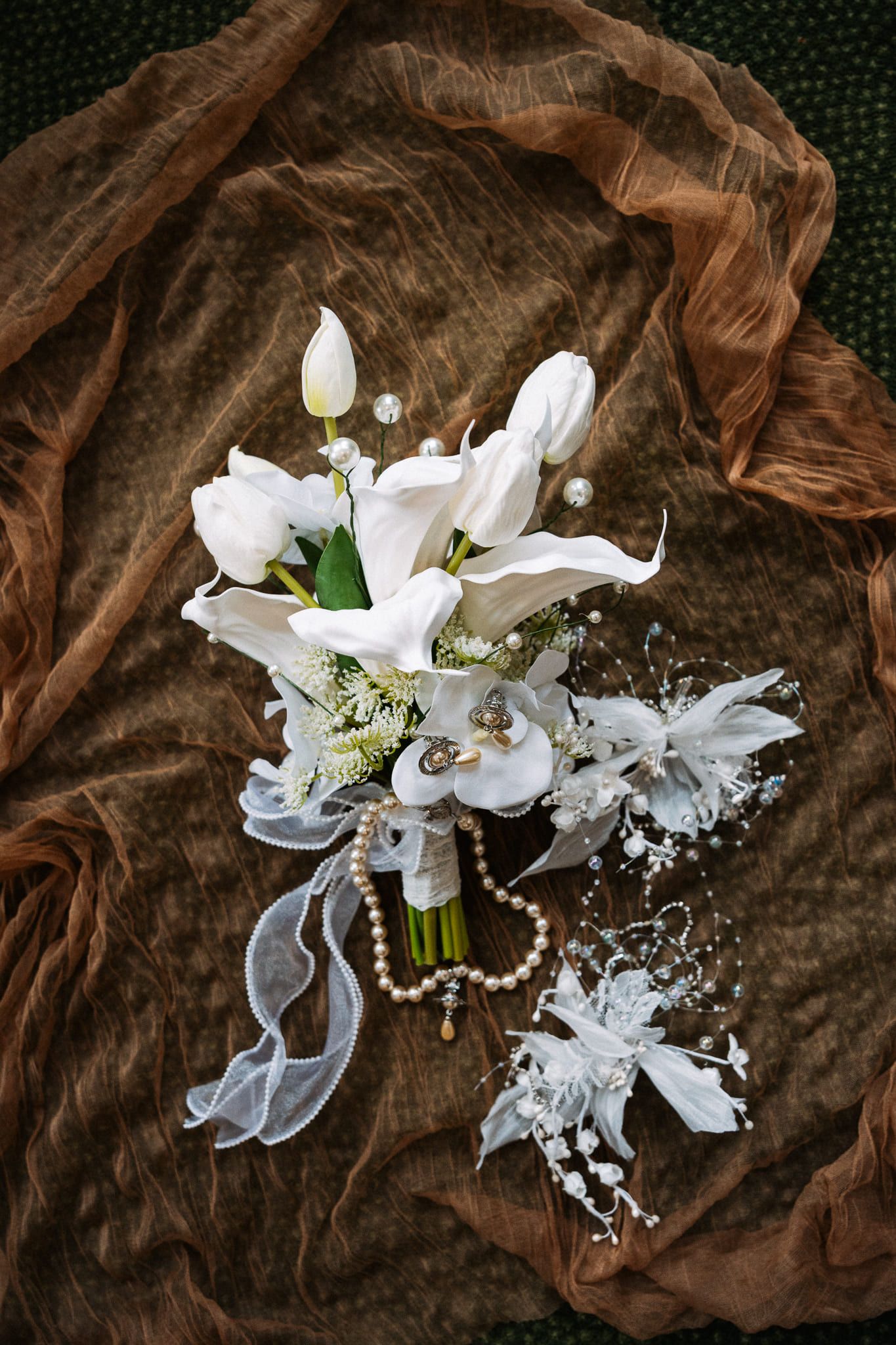 Creative wedding photos, white bridal bouquet with pearls on brown silk