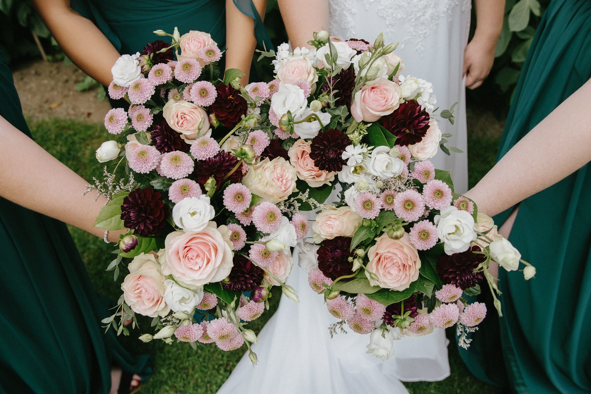 Bridal photography, bridesmaids holding bouquets of pink and burgundy flowers together