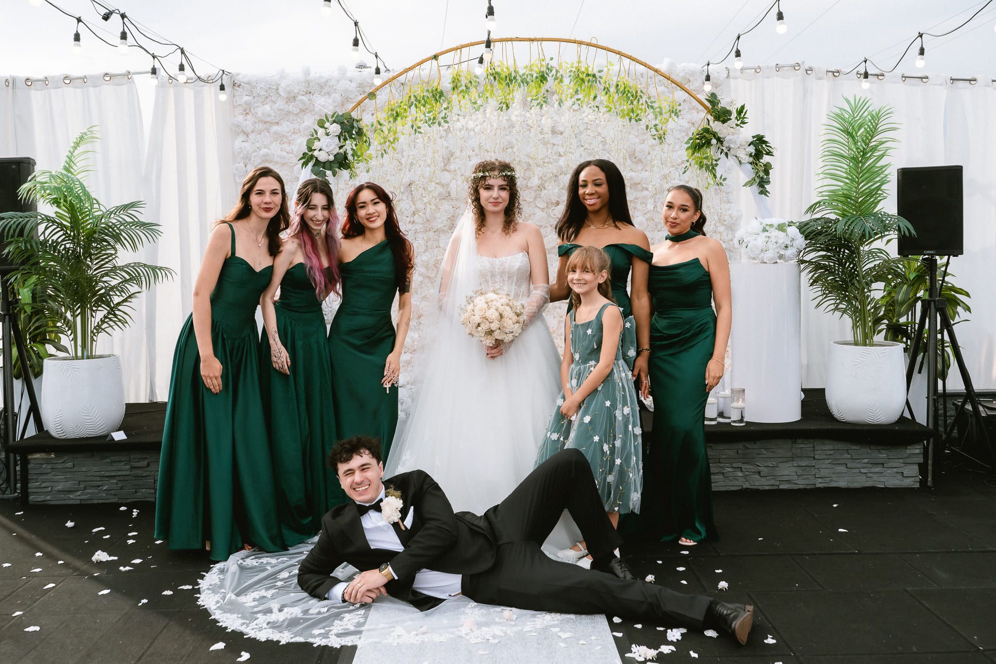 Bridal photography, bride and her bridesmaids in green with a groomsman lying at their feet