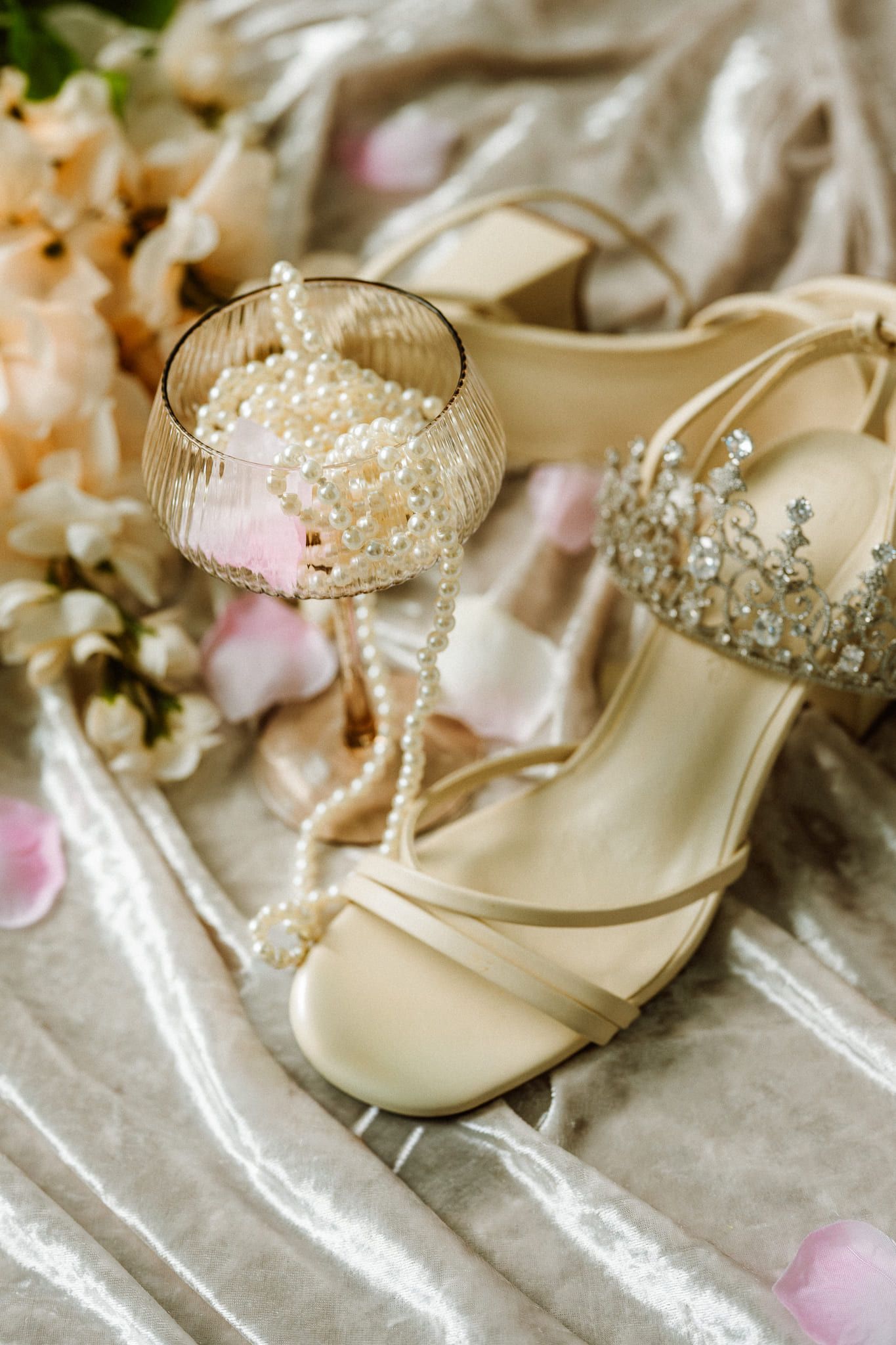 Elopement photos, bridal shoes, a pearl necklace and a tiara on satin