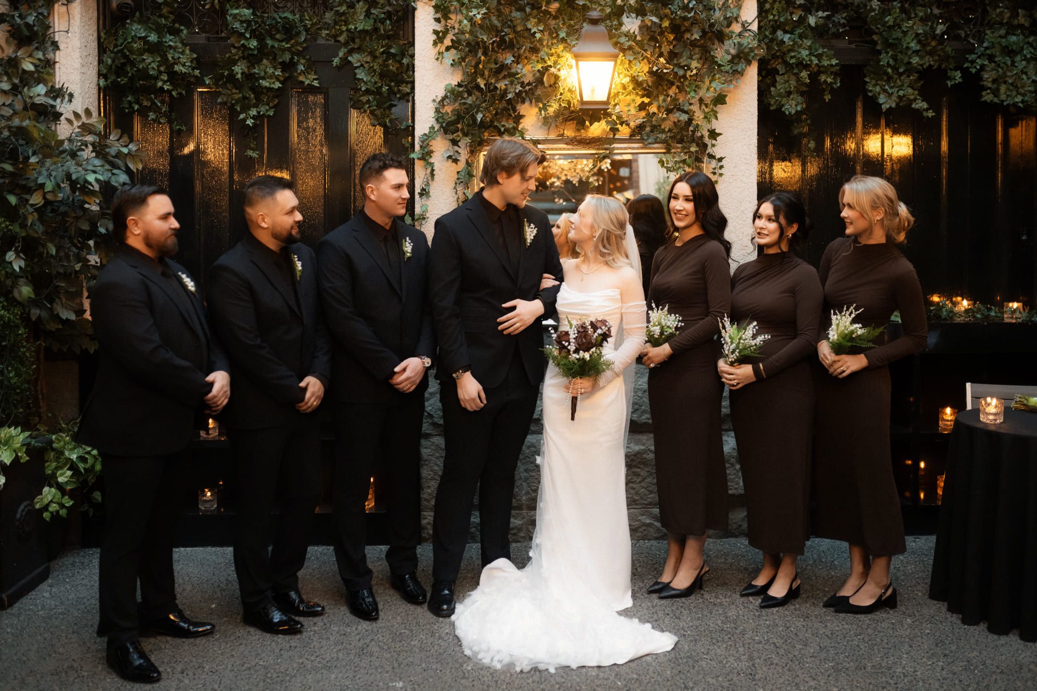 Wedding shoot, wedding party in black around the bride and groom at an evening reception
