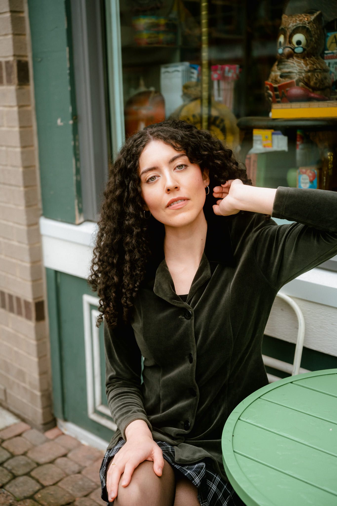 Indoor portrait photography by a shop window, woman sitting at a green café table