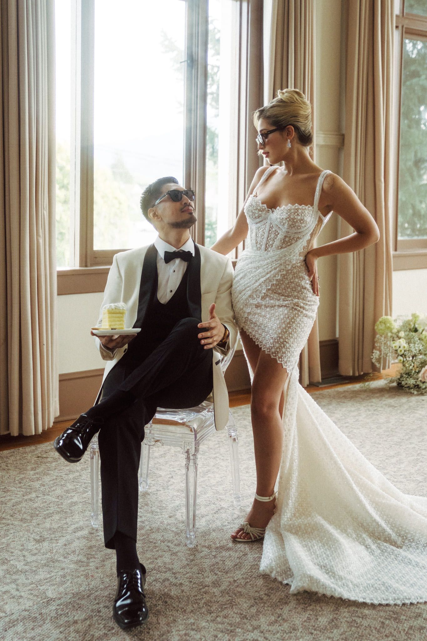 Indoor wedding photos by a tall window, bride and groom posing on a chair