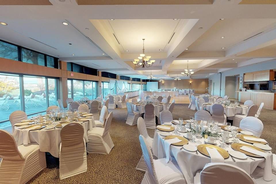 Indoor wedding photoshoot beside tall windows, reception room with round tables