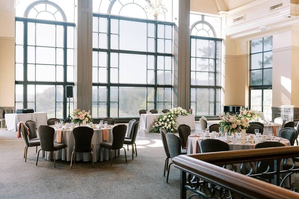 Wedding indoor photoshoot, bright reception room with arched windows and round tables