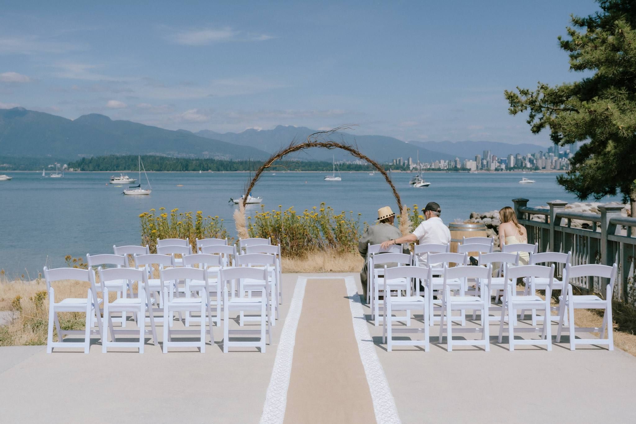 White chairs and a driftwood arch set for the ceremony by the water