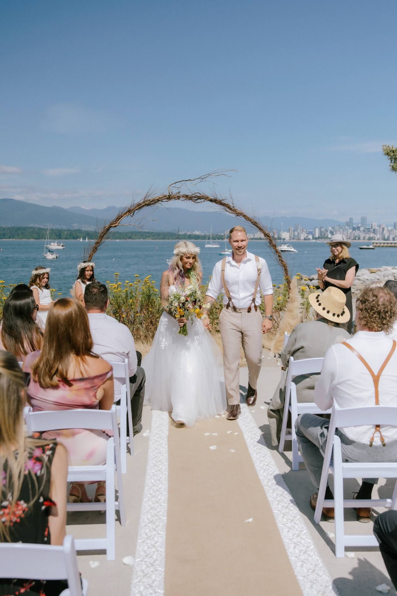 Bride and groom at the driftwood arch before their guests