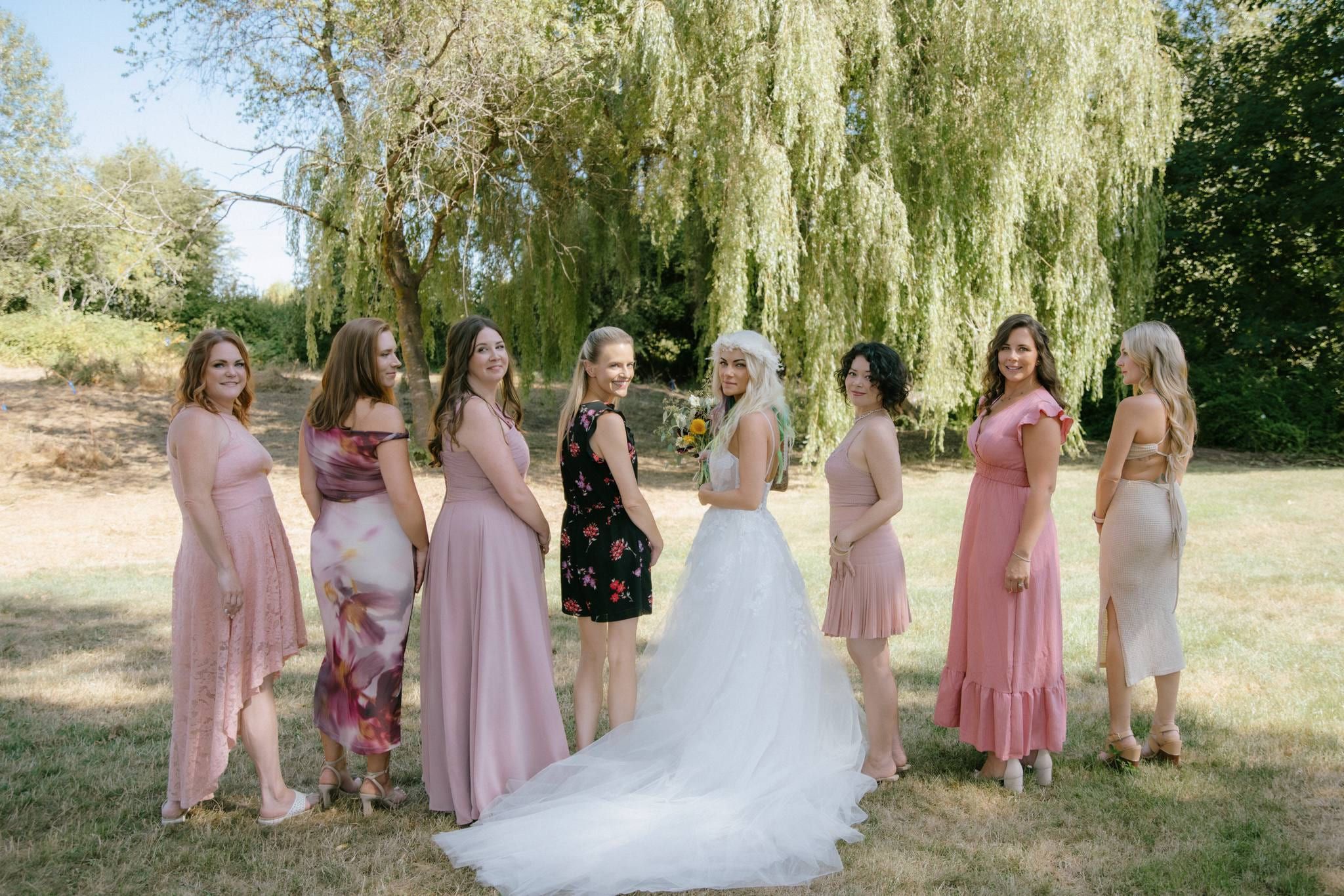 Bride with bridesmaids in pink dresses beneath a willow tree
